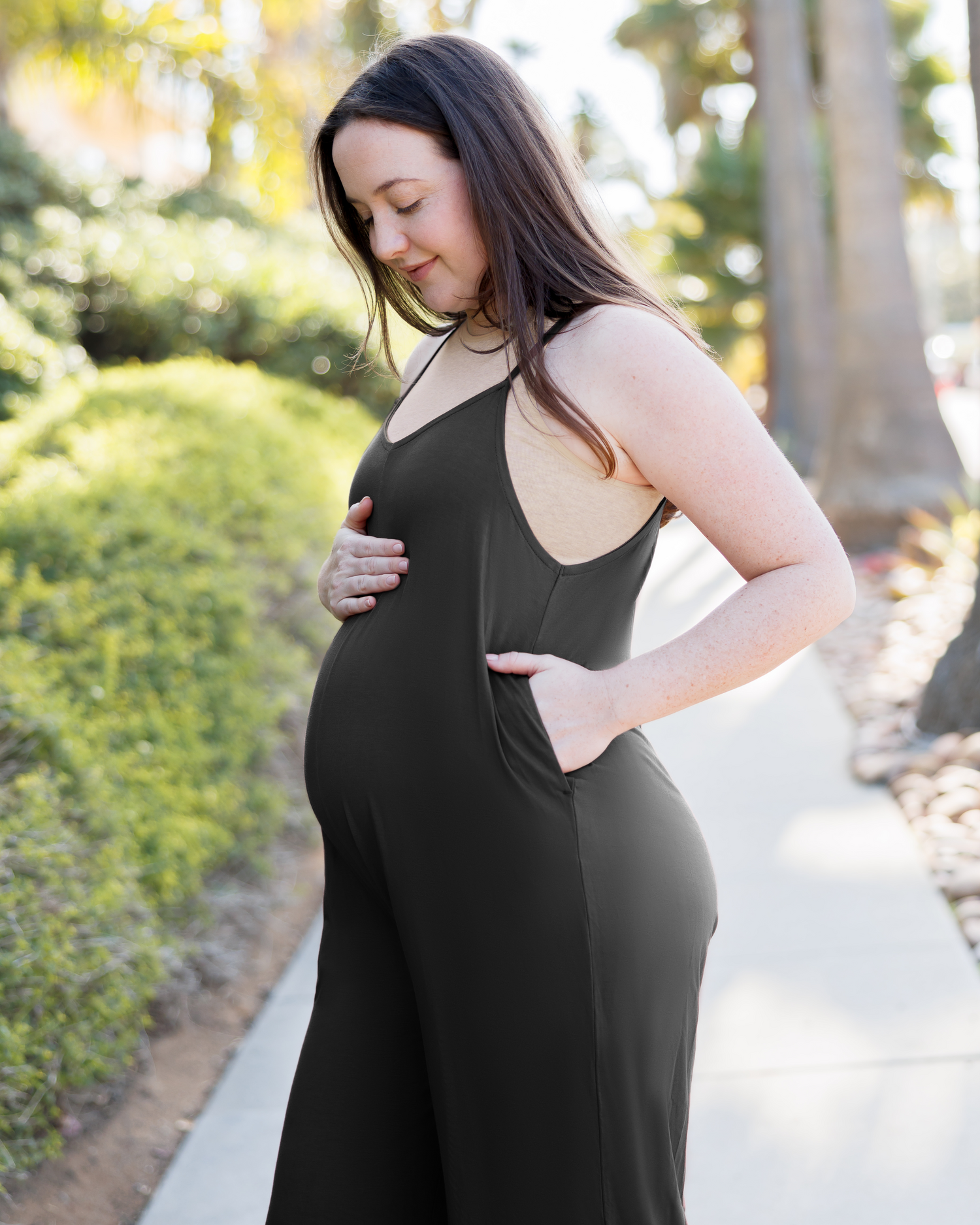Close up of pregnant model wearing the Charlie Maternity & Nursing Romper in Black, with hand in pocket