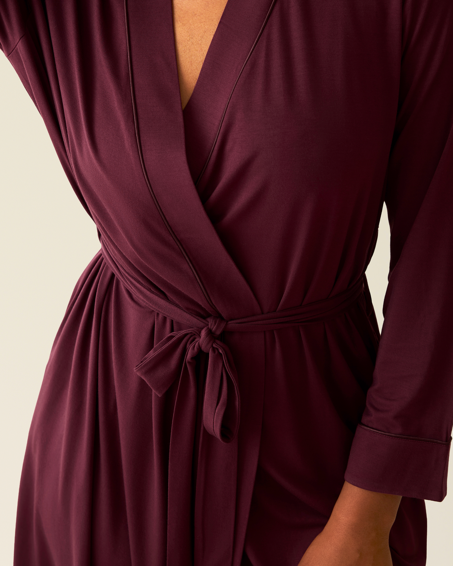 Woman wearing the Clea Bamboo Robe in Deep Burgundy, showing piping and tie detail