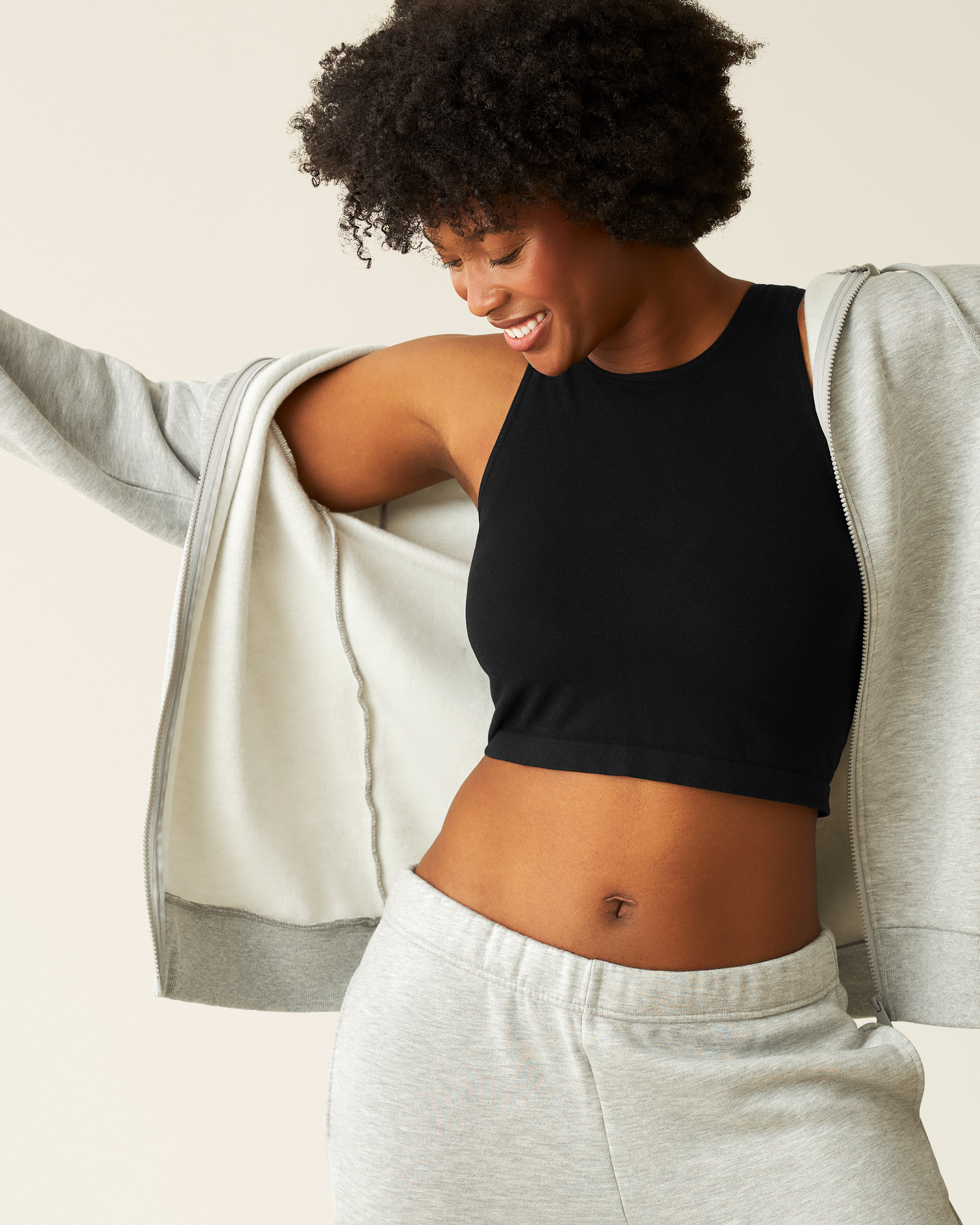 Woman wearing the Cloud Fleece Oversized Hoodie in Grey Heather, unzipped with Black Longline Bra Top underneath and Cloud Fleece Grey Heather bottoms