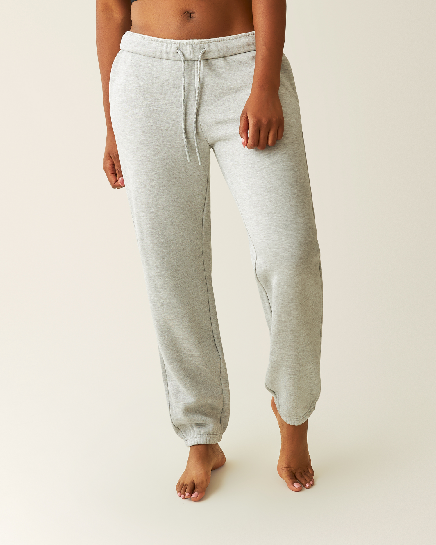 Cropped in view of woman wearing the Cloud Fleece Jogger in Grey Heather@model_info:Kyra is 5'9" and wearing a Small.