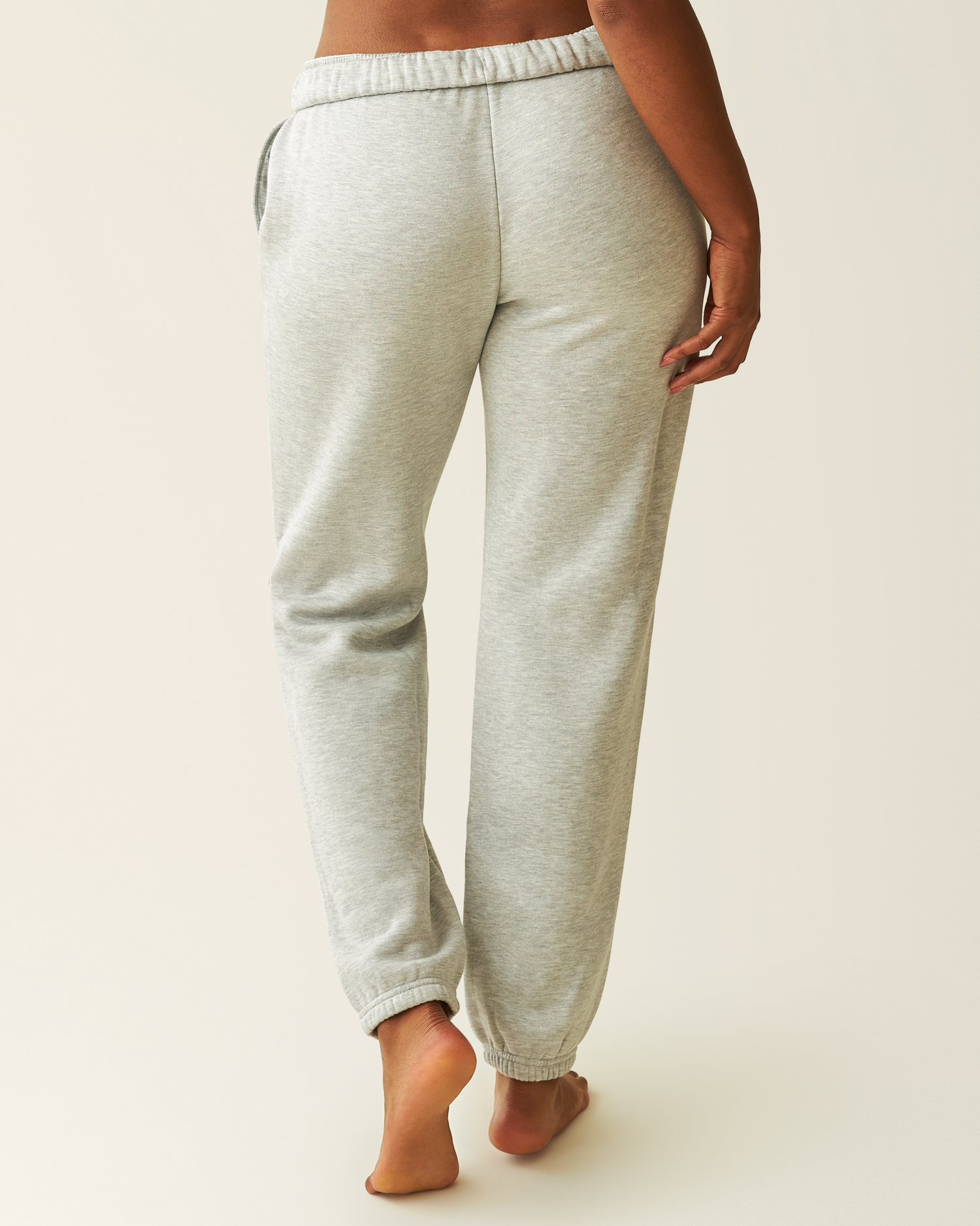 Back of the Cloud Fleece Jogger in Grey Heather worn by a woman on a plain background