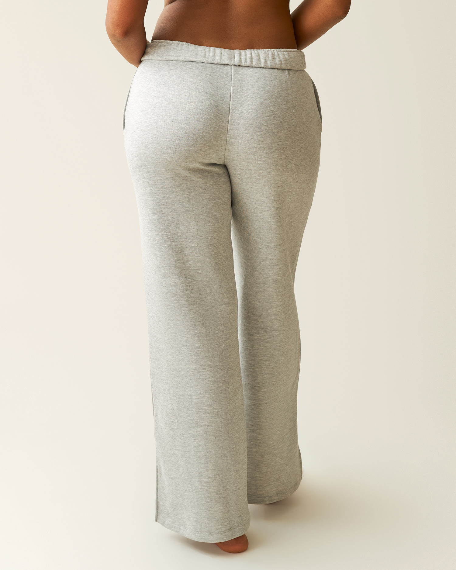 Back of woman wearing heather grey Cloud Fleece Sweatpant on a beige background