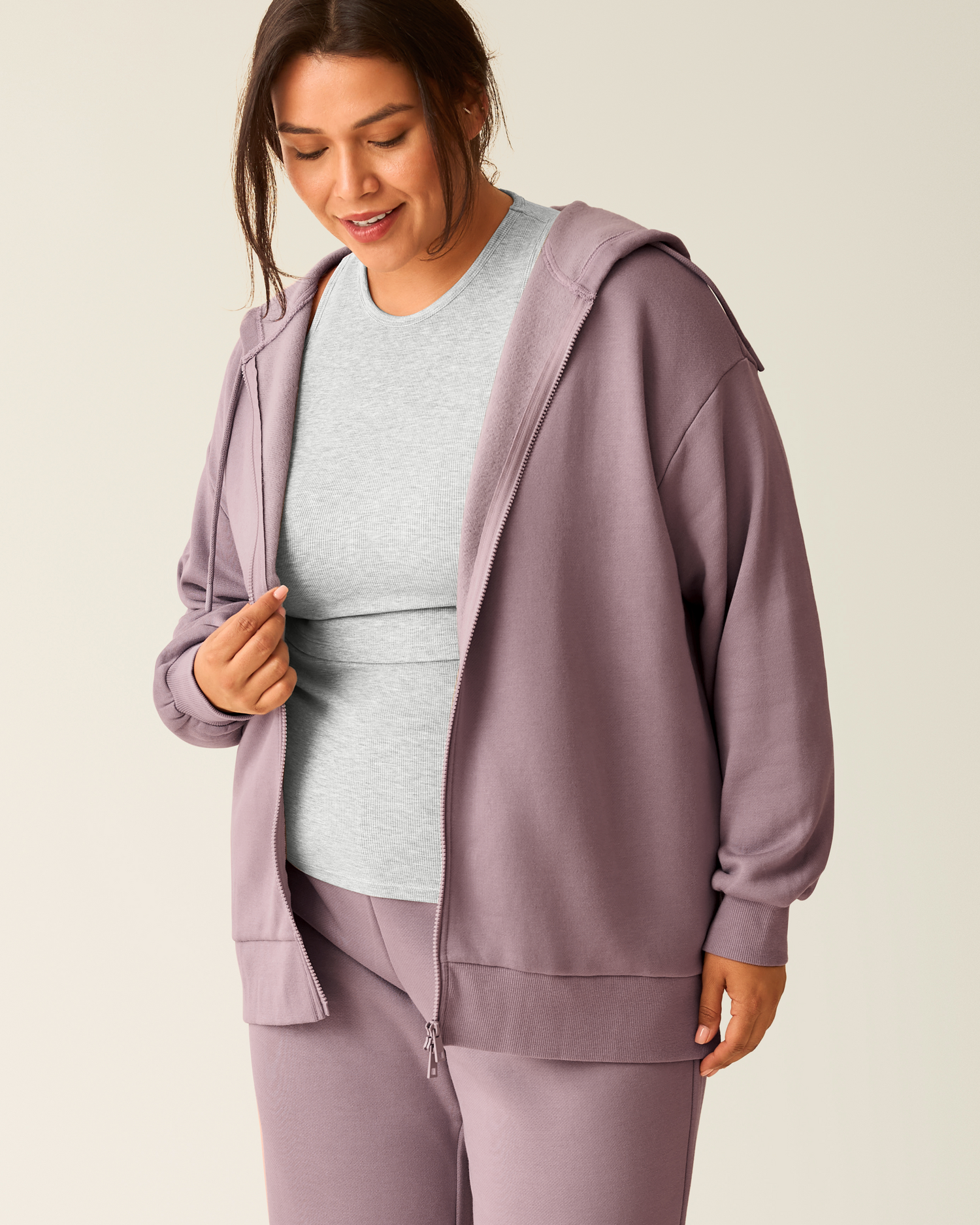 Woman wearing the Cloud Fleece Oversized Hoodie in Dusty Mauve unzipped with light grey top underneath@model_info:Victoria is wearing a 1X.