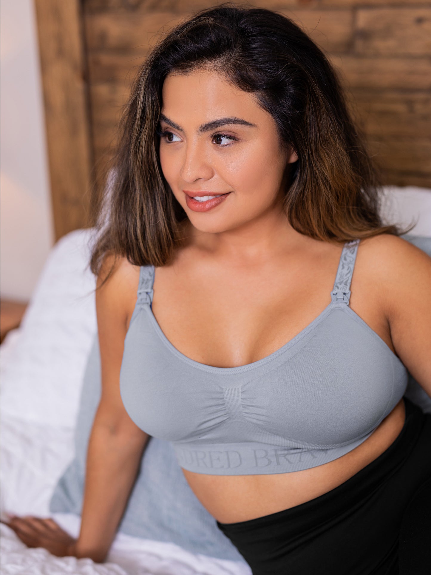 Model wearing the Simply Sublime® Nursing Bra in grey against a bed