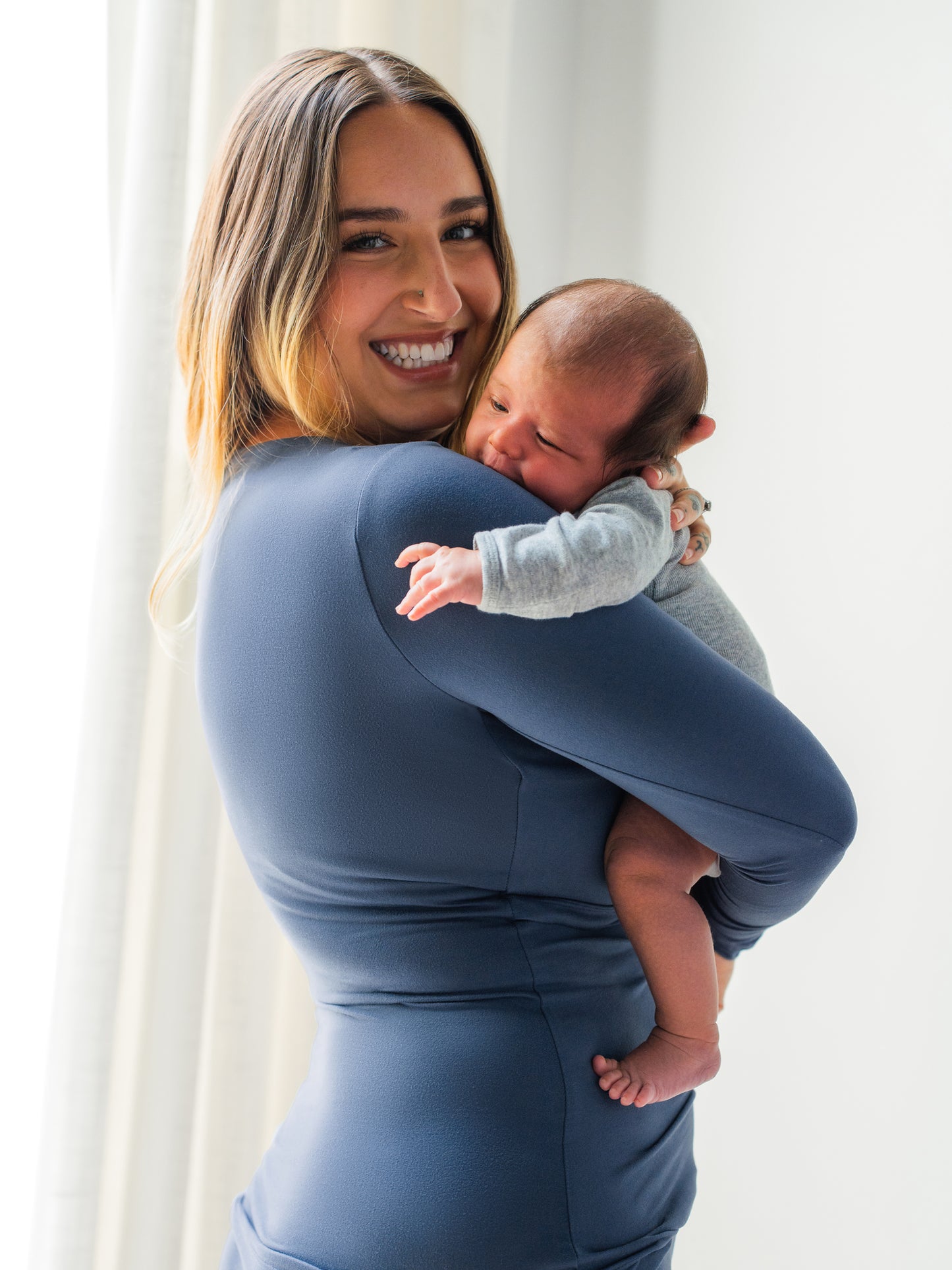 Model wearing the Jane Nursing Pajama Set in Slate Blue and holding baby.