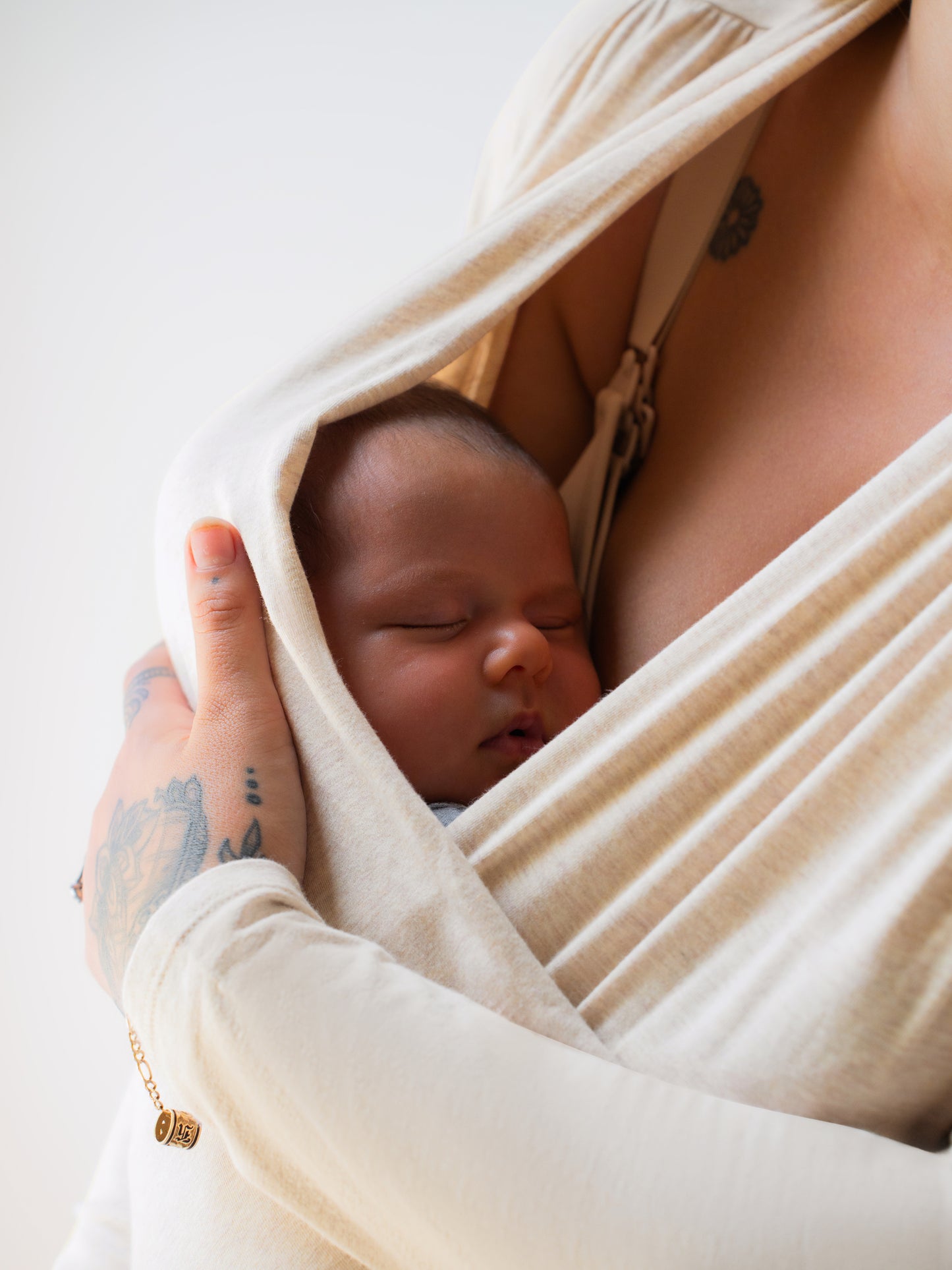 Close up of baby wrapped in the Organic Cotton Skin to Skin Long Sleeve Wrap Top in Oatmeal Heather, worn by model mom.