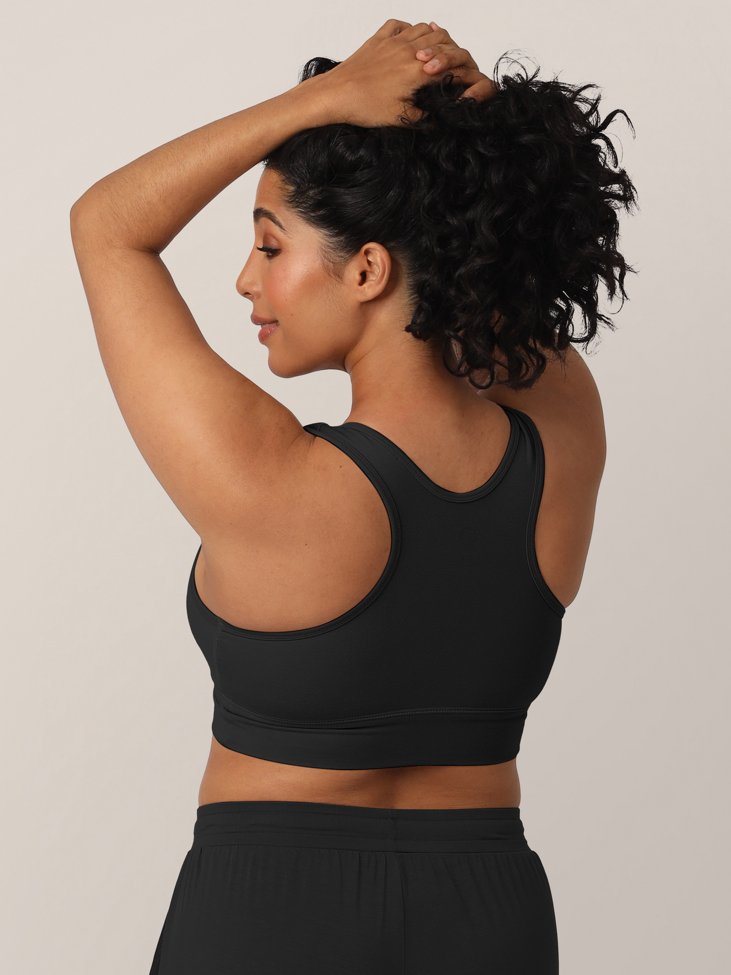 Back view of model wearing the French Terry Nursing Bra in Black and holding her hair up to show the racerback detail.