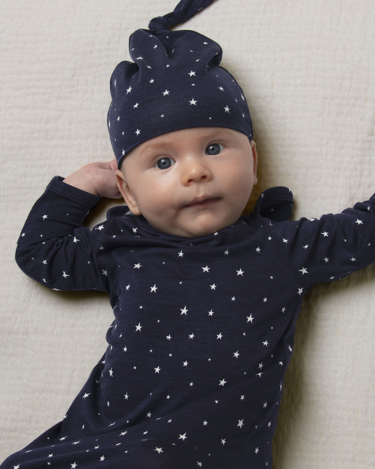 Baby wearing Bamboo Knotted Baby Gown in Navy Stars on a beige background