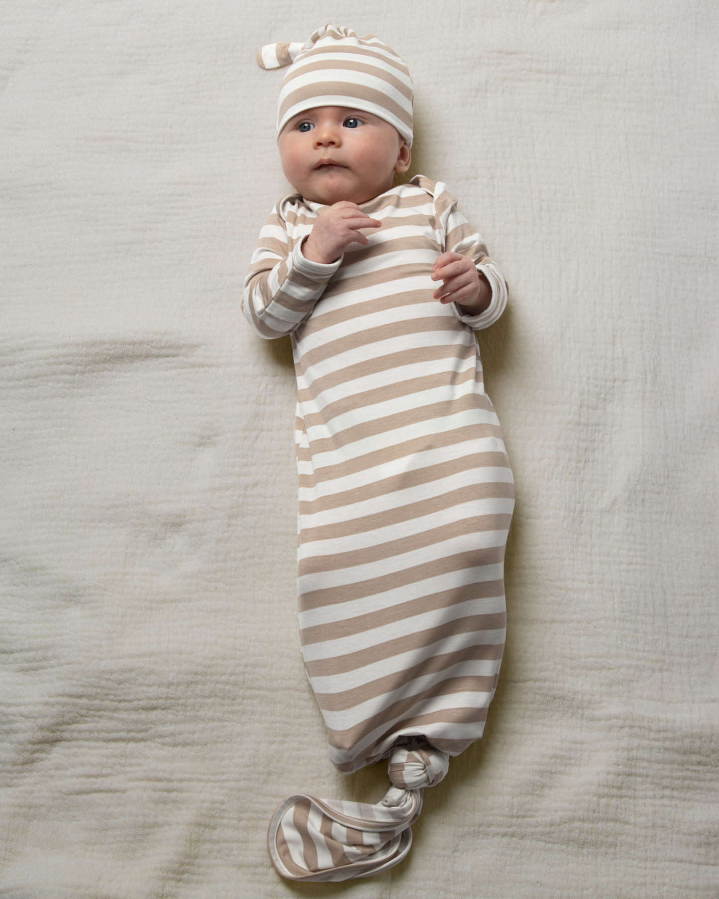 Baby wrapped in Bamboo Knotted Baby Gown in Fawn Stripe on a neutral background