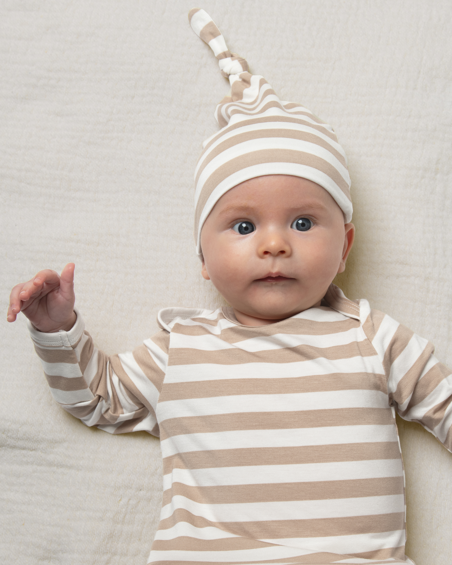 Baby wearing Bamboo Knotted Baby Gown in Fawn Stripe on a neutral background