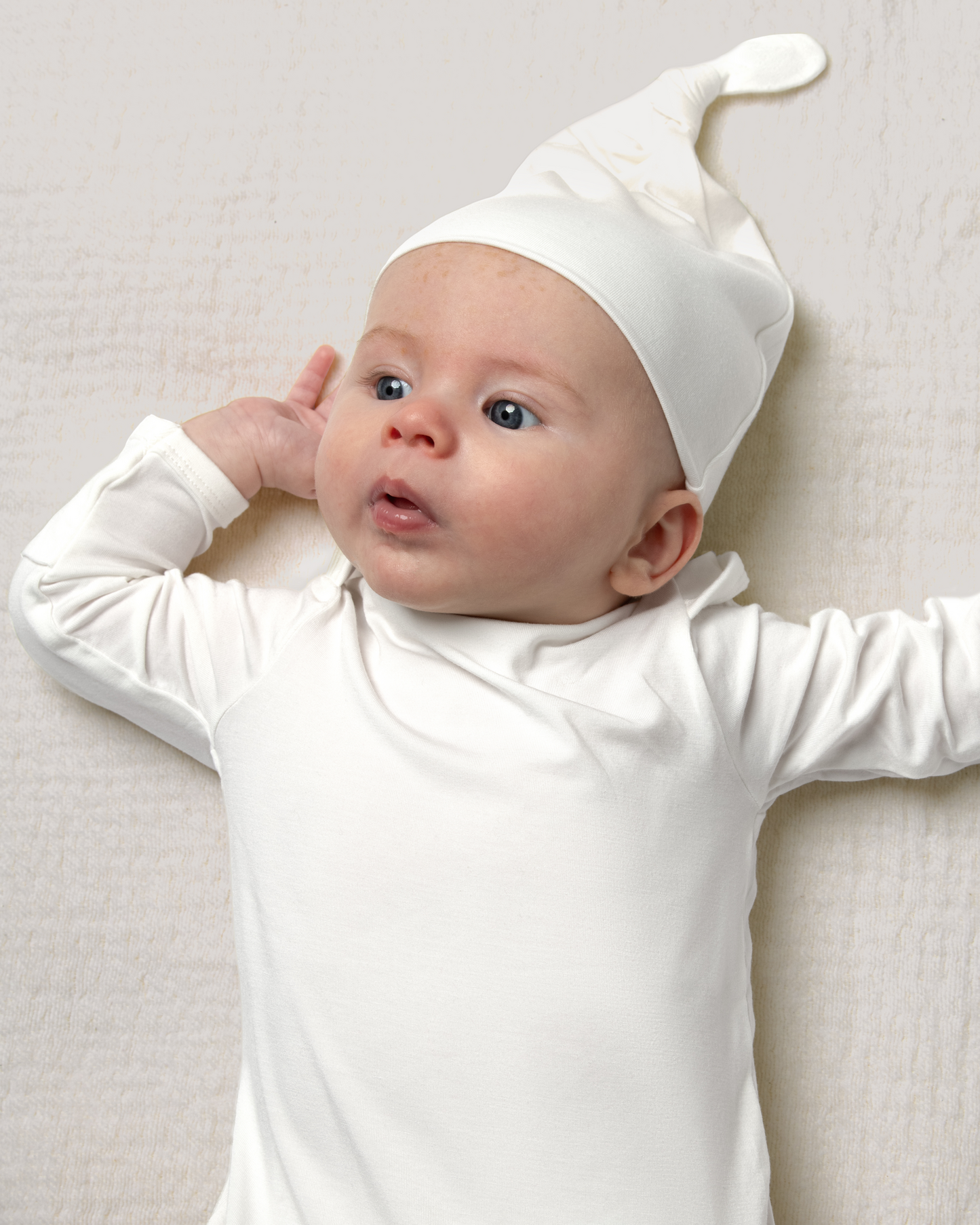 Baby wearing Bamboo Knotted Baby Gown in Pearl on a light background