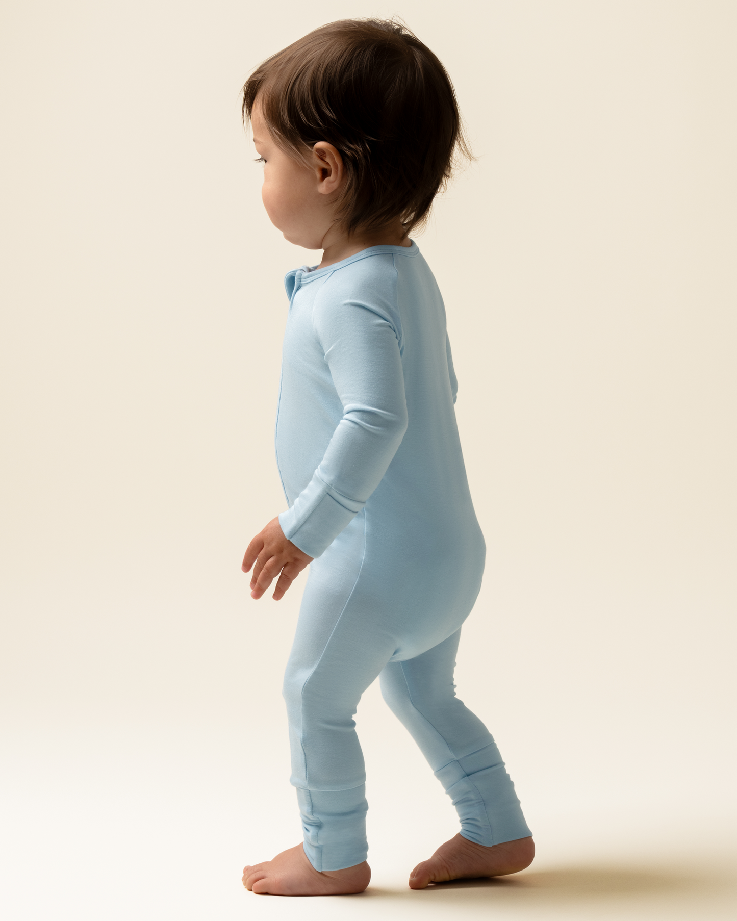 Child wearing Bamboo Baby Pajamas in French Blue against a beige background