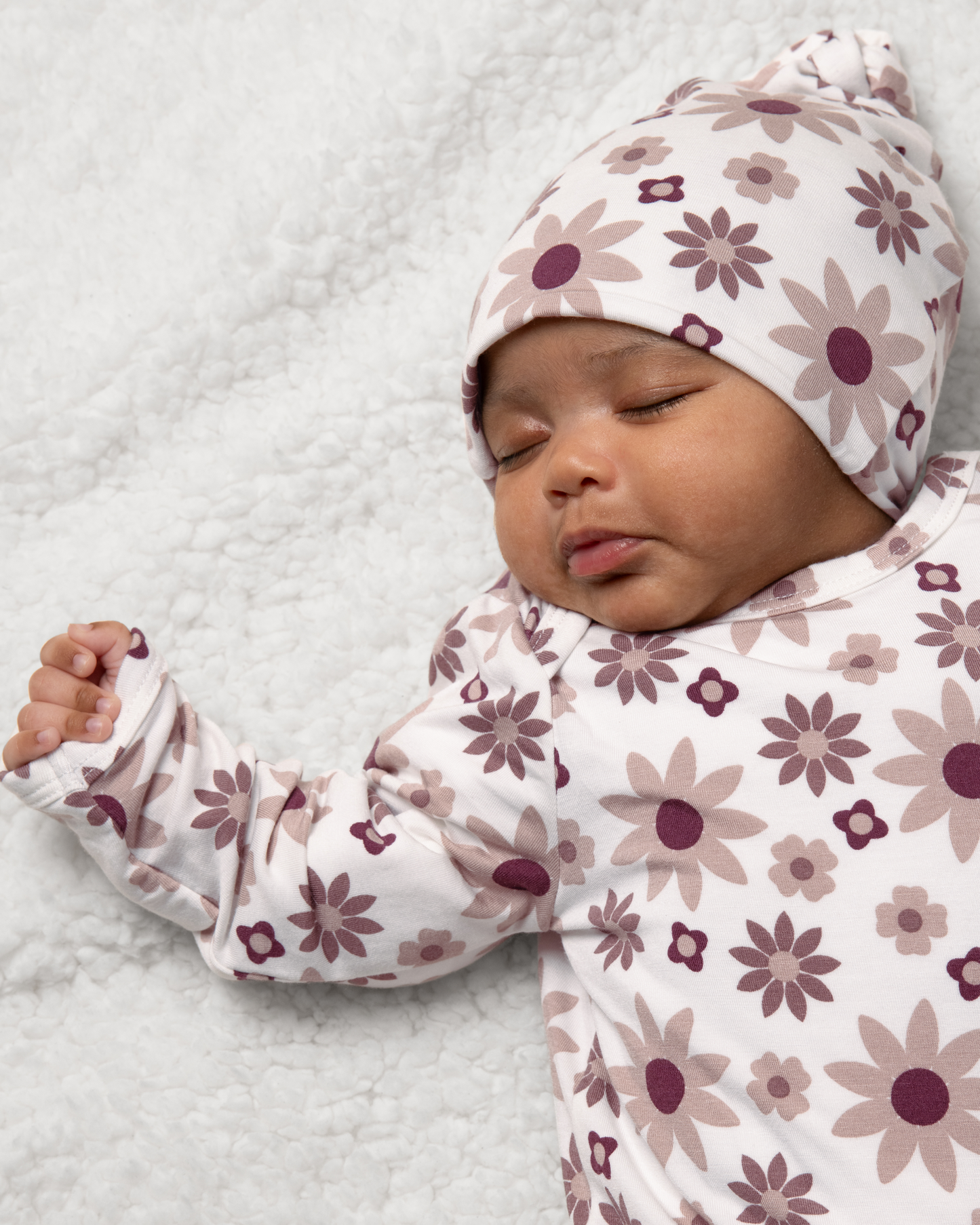 Baby wearing Bamboo Knotted Baby Gown in Twilight Floral on a soft surface