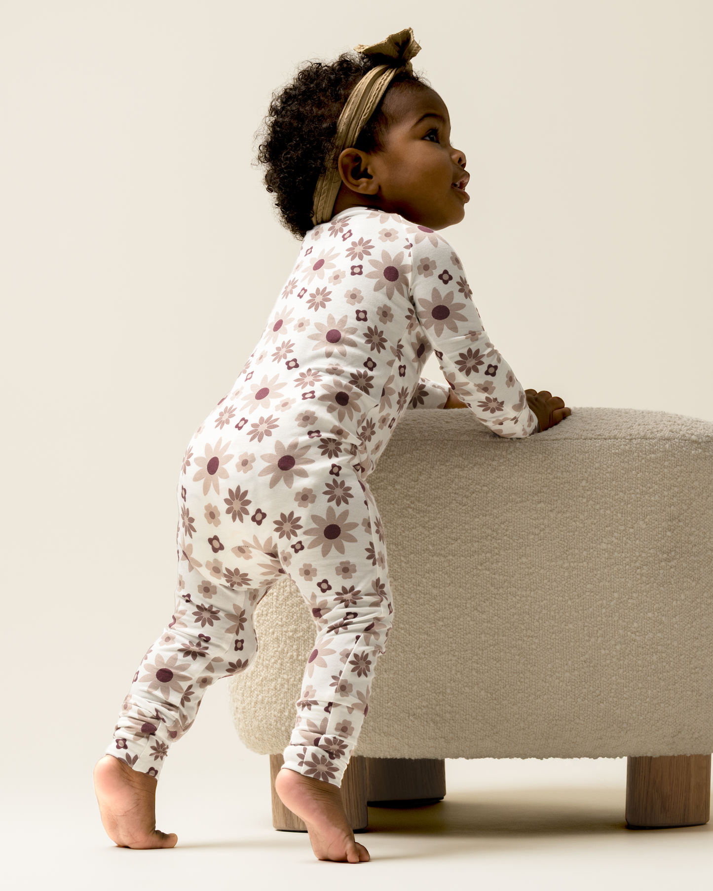 Child in Bamboo Baby Pajamas in Twilight Floral standing on a small stool against a plain background