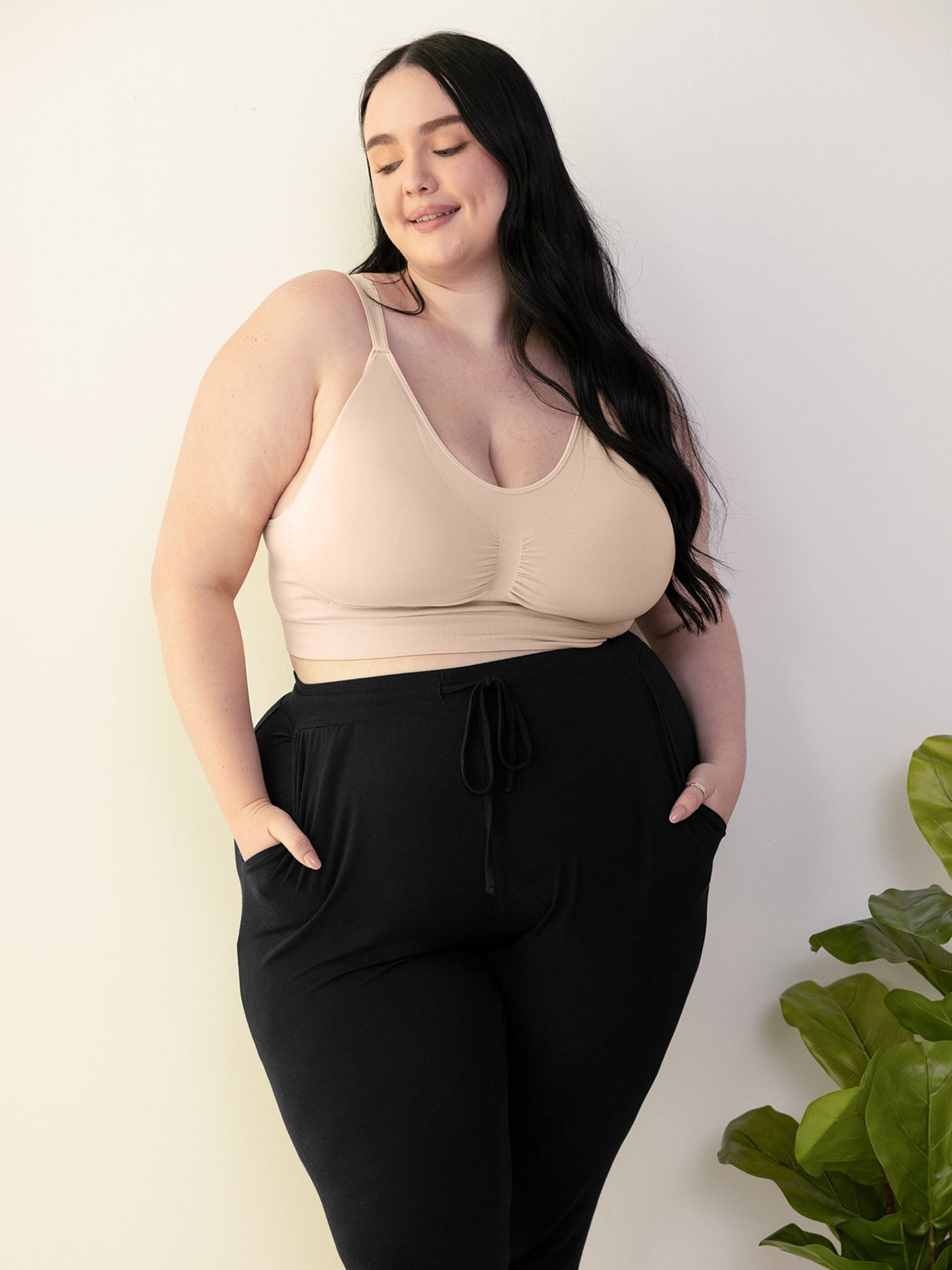 Model wearing the Nellie Wireless Bra in beige, with her hands in her pockets. @model_info:Kenna is wearing a 2X Busty. 