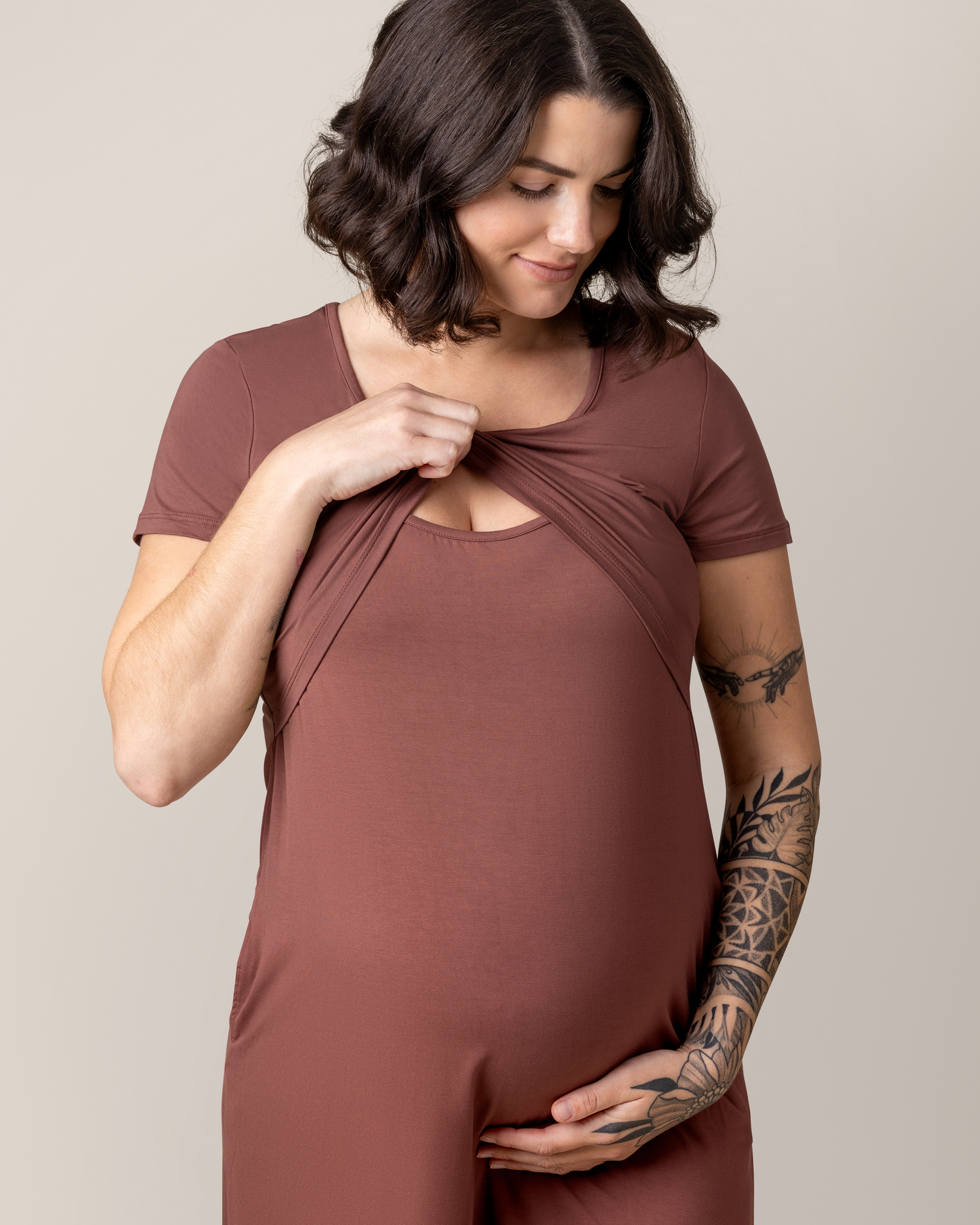 Close up of model wearing the Eleanora Bamboo Maternity & Nursing Dress in Redwood, lifting up top outer layer to show nursing access. @model_info:Emily is 5'8" and wearing a Medium.