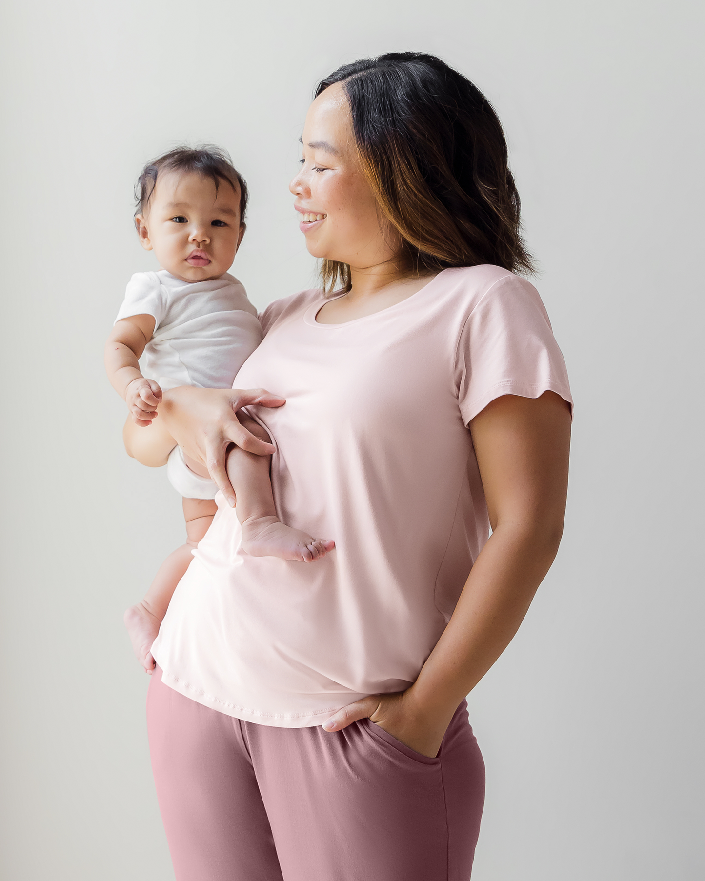 Model wearing the Everyday Maternity & Nursing T-shirt in Dusty Pink and holding baby @model_info:Elizabeth is wearing a Large.