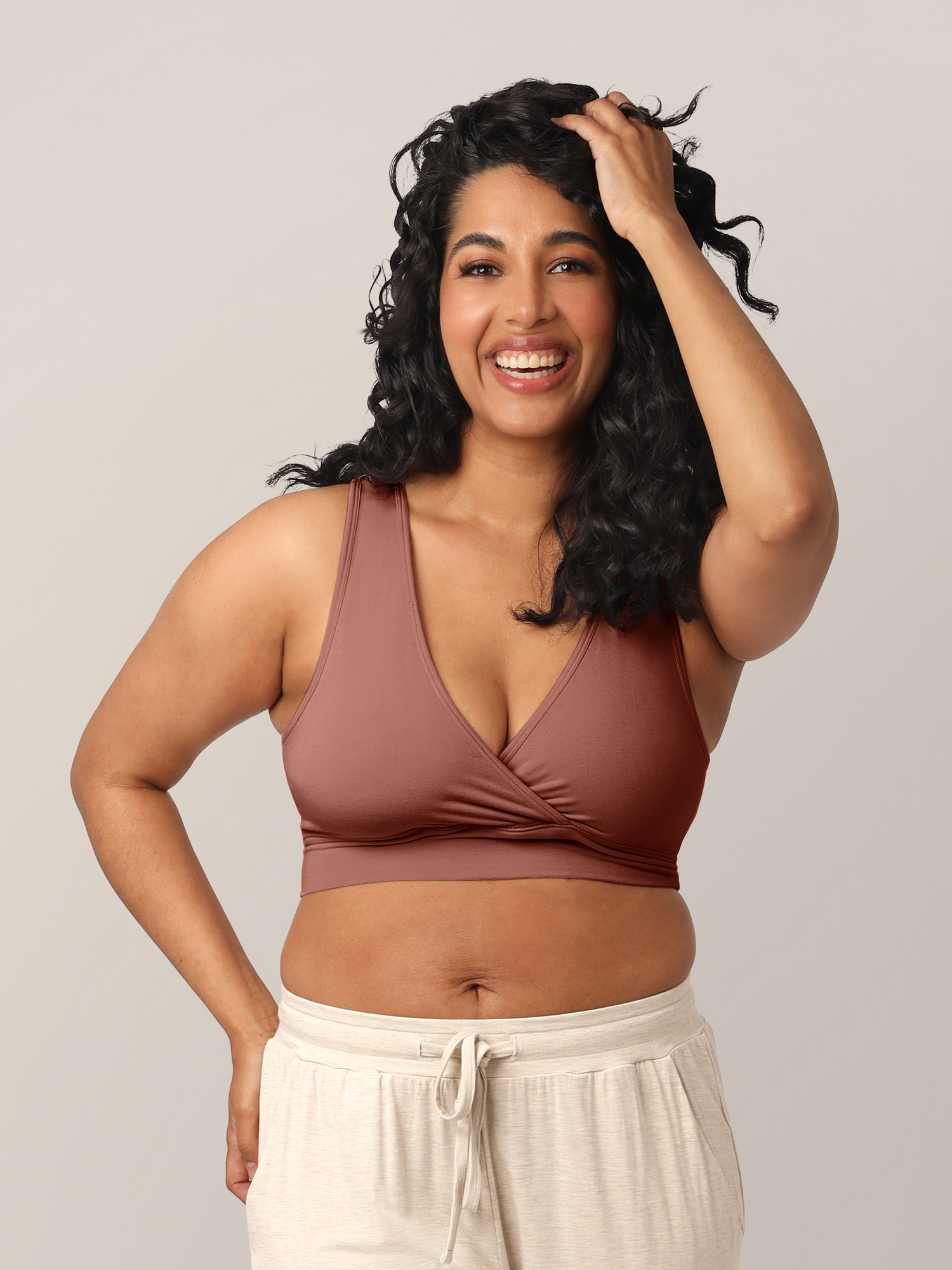 Model wearing the French Terry Nursing Bra in Redwood and playing with her long curly hair. @model_info:Zakeeya is wearing a Small.