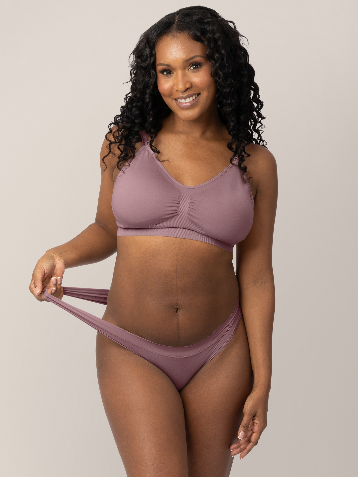 Model wearing the Grow with Me™ Maternity & Postpartum Thong in Twilight holding onto the stretchy waistband on the thong. @model_info:Rashé is wearing a Medium.
