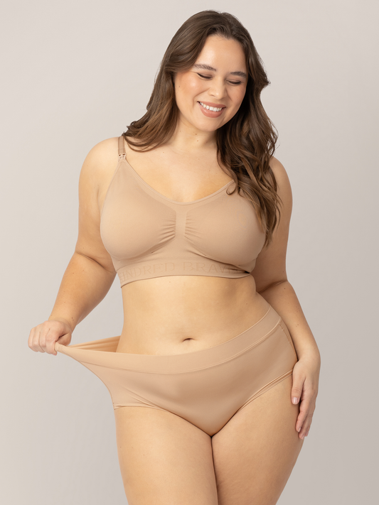 Model tugging on the waistband of her Grow with Me™ Maternity & Postpartum Brief in Beige.  @model_info:Venezia is wearing a Large.