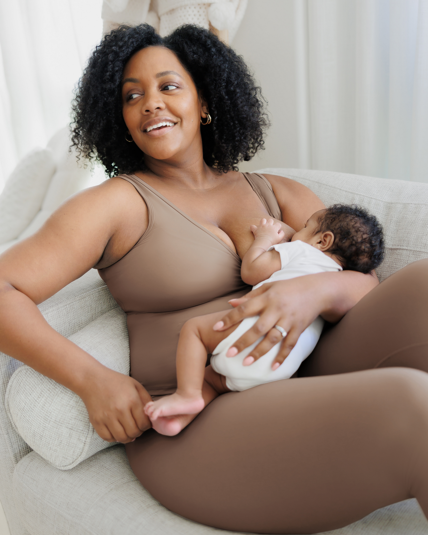 Model on sofa nursing baby, wearing the Grow with Me™ Maternity & Nursing Tank in Taupe paired with matching Grow with Me™ Maternity & Postpartum Legging