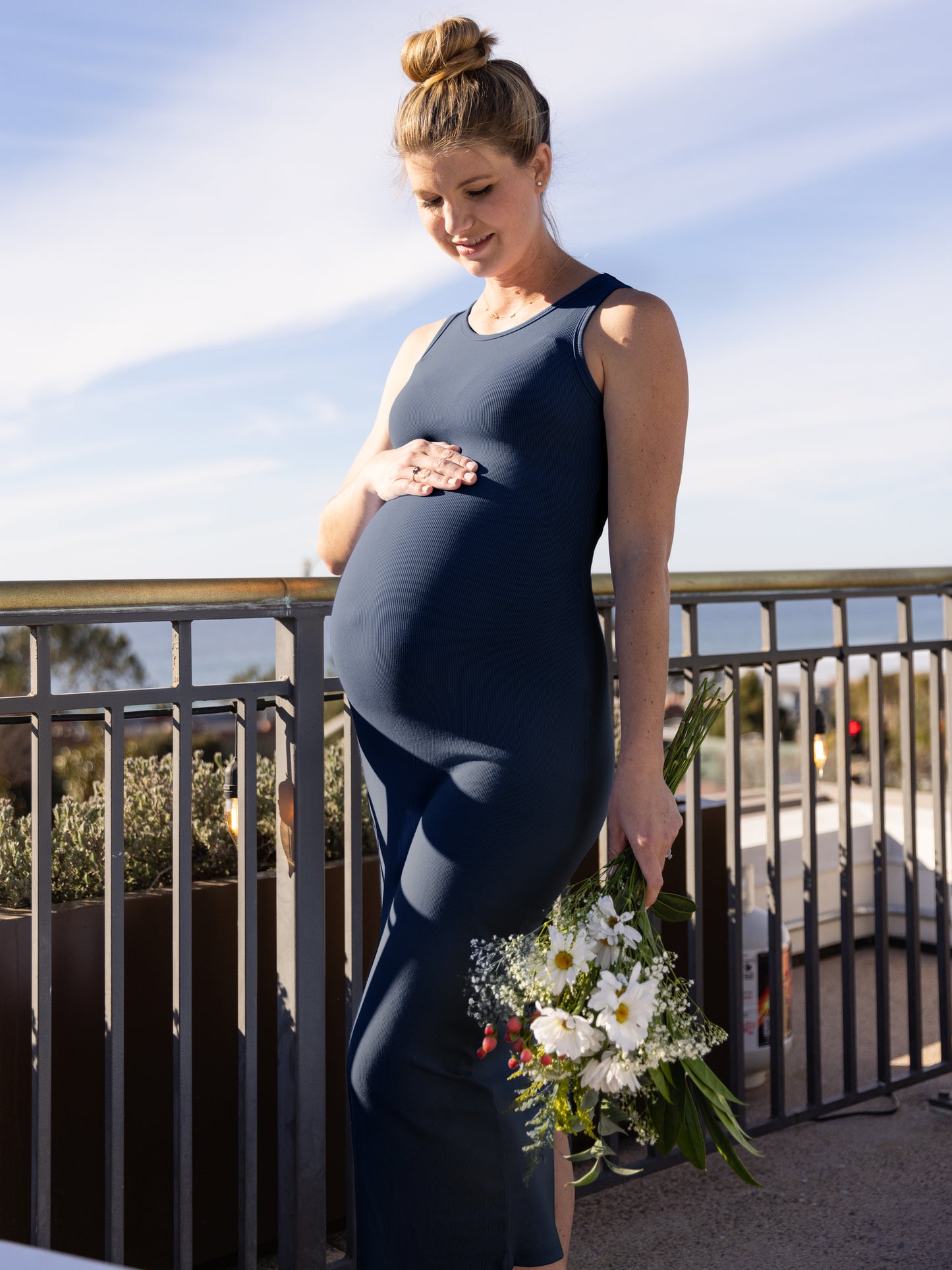 Outside picture of a pregnant model wearing the Gwen Ribbed Bamboo Maternity Midi Dress in Navy.@model_info:Amber is wearing a Small.