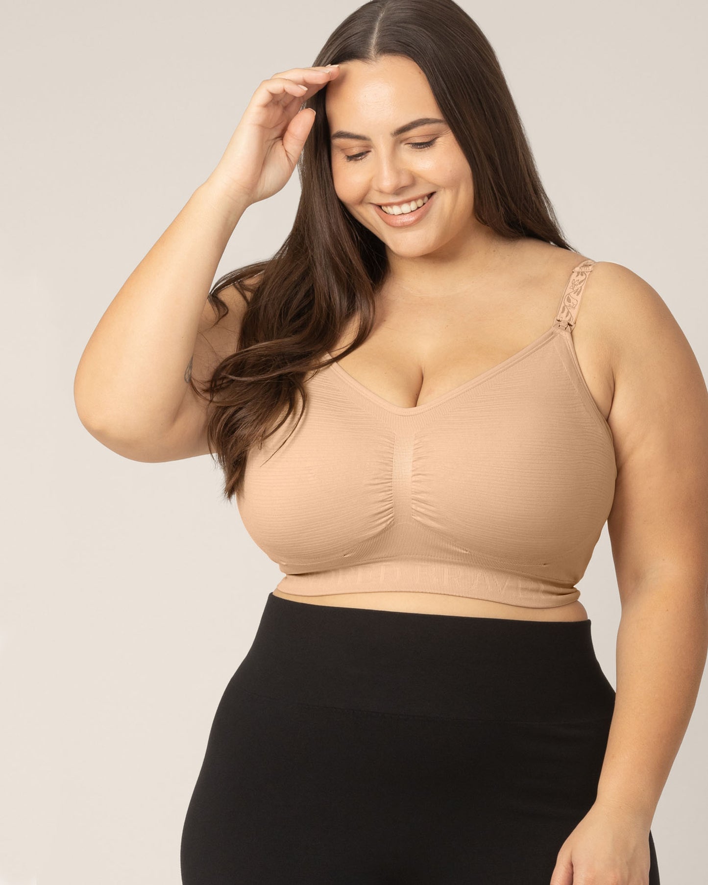 Super-Busty model looking down wearing the Sublime® Hands-Free Pumping & Nursing Bra in Beige.@model_info:Anna is wearing a Large Super Busty.