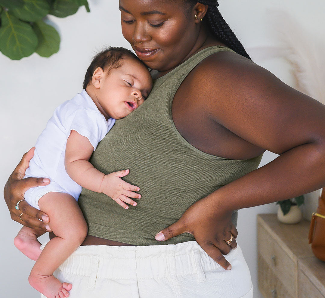 Side view of model wearing the
Sublime® Bamboo Maternity & Nursing Longline Bra in Olive Heather, holding infant resting on her chest