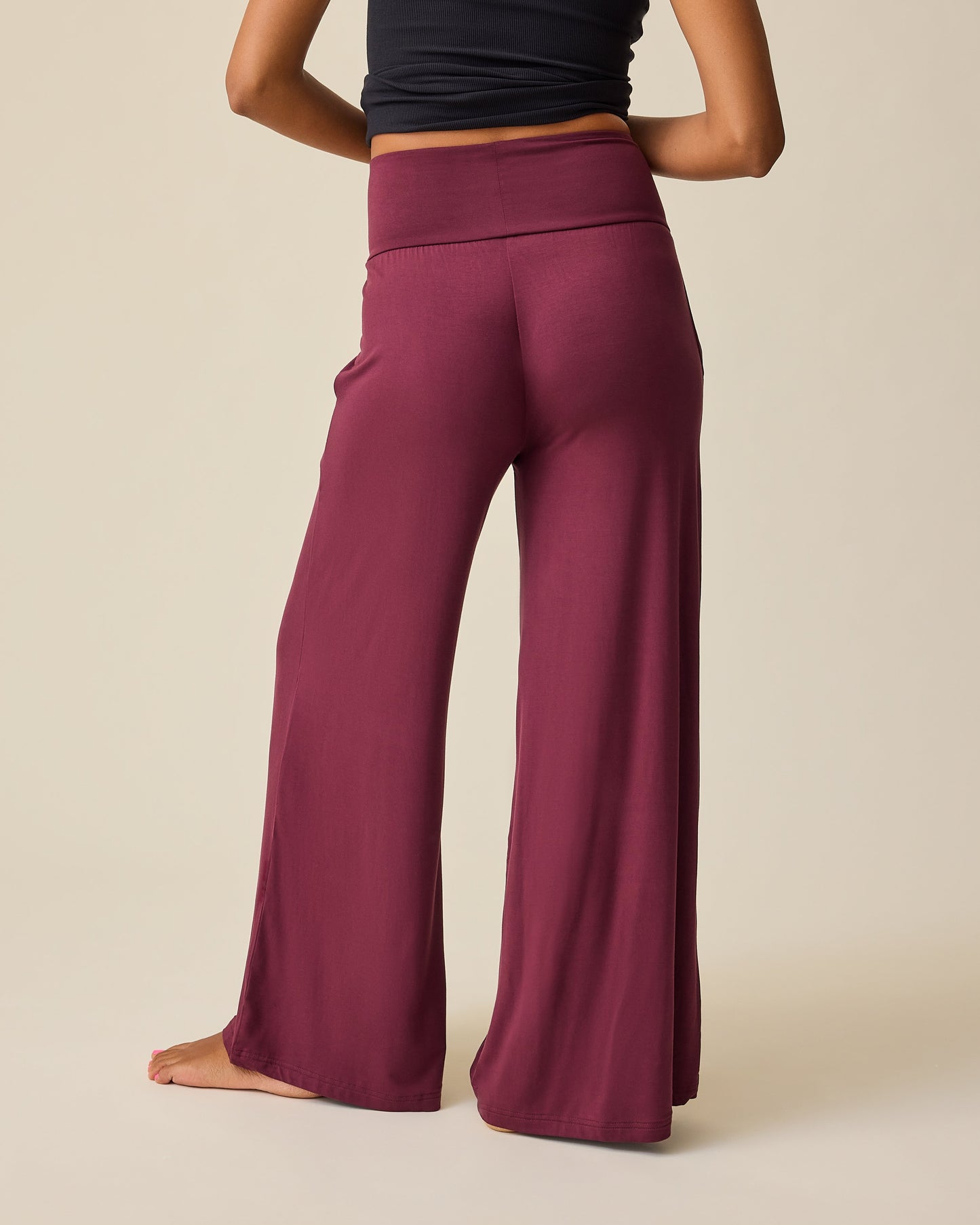 Back view of model wearing Bamboo Wide Leg Maternity & Postpartum Lounge Pant in Fig and Ribbed Bamboo Racerback Nursing Tank in Black on a beige background.