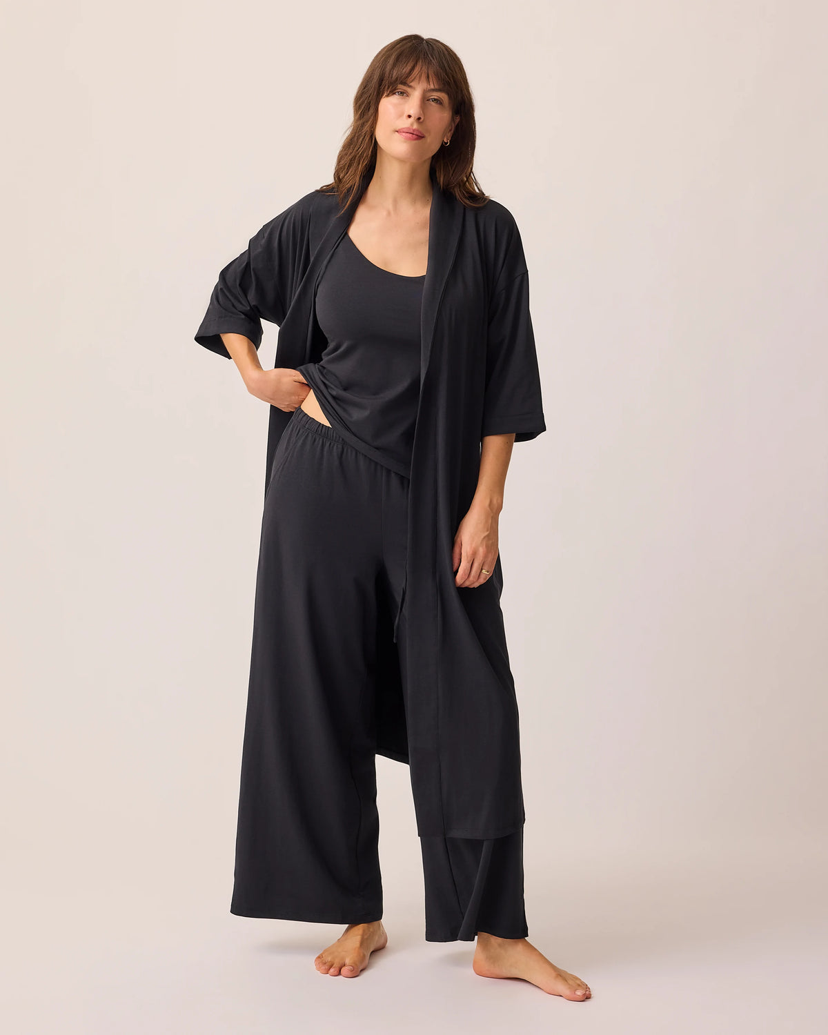 Model is wearing Robe slightly opened of the Maternity & Nursing Three-Piece Pajama Set in Black, on a beige background.