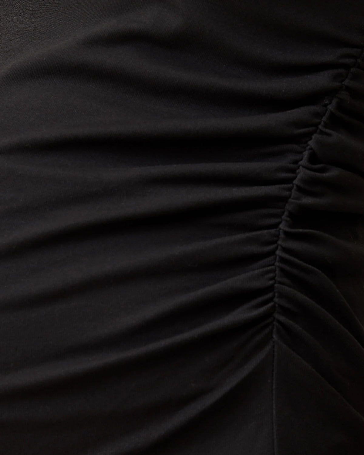 Close up of ruched side of the Ruched Maternity Sleeveless Top in Black on a beige background.