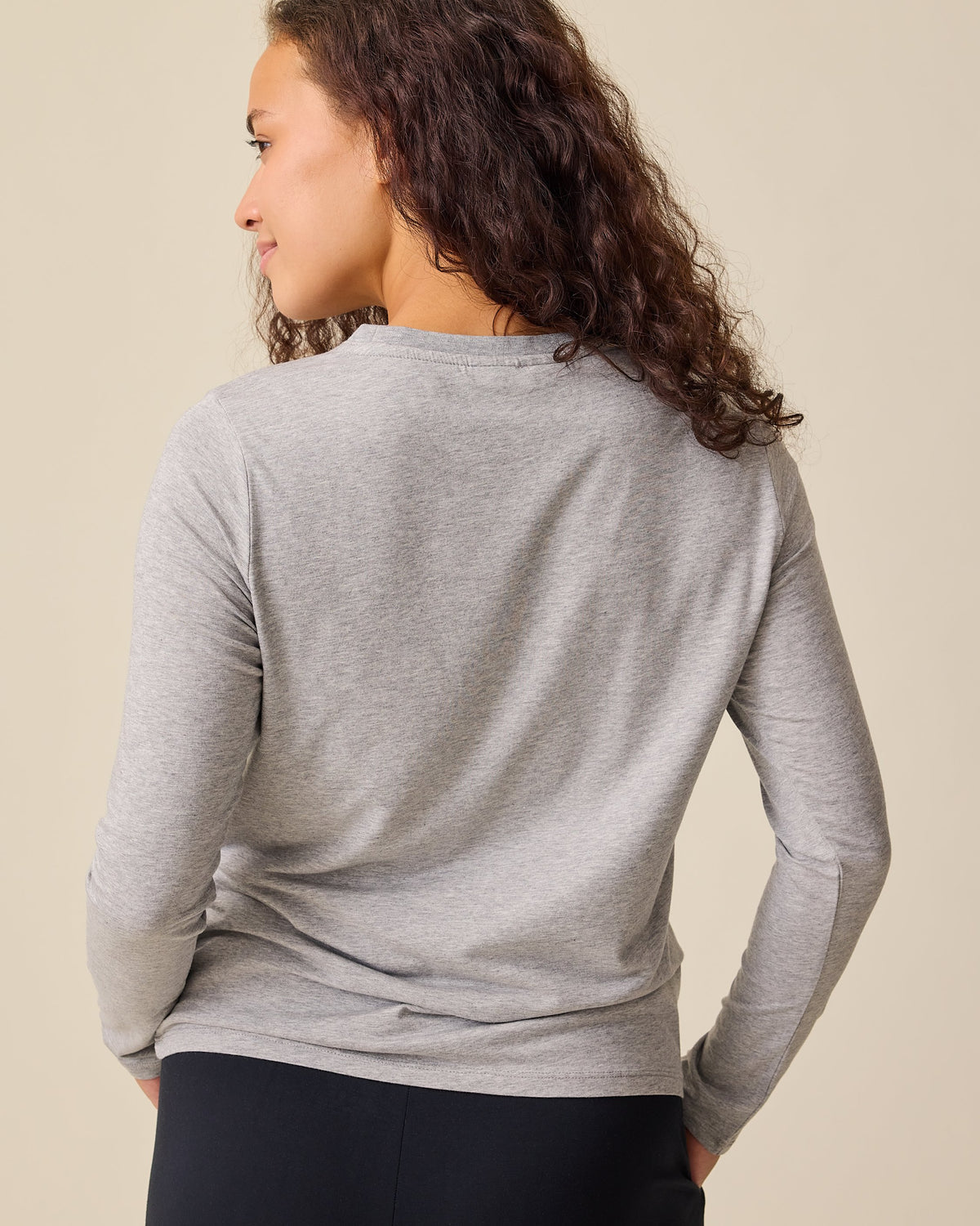 Back view of the model wearing the Modal Long Sleeve Nursing T-shirt in Grey Heather on a beige background.