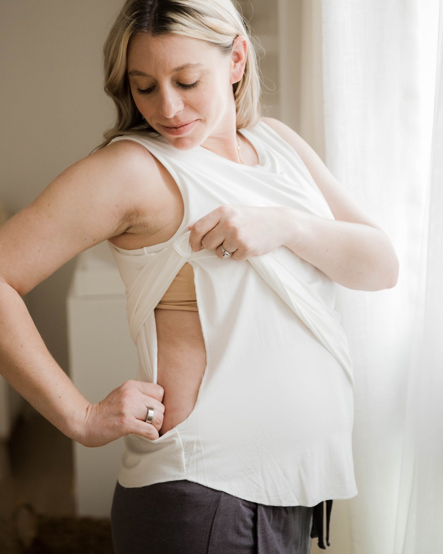 Model wearing the Bamboo Maternity & Nursing Tank in white, pulling aside layers to show nursing access
