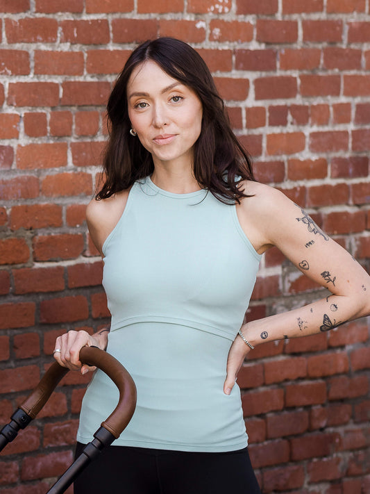 model wearing the Ribbed Bamboo Racerback Nursing Tank in dusty blue green, outside with hand on stroller handle @model_info:Lyn is wearing a Small.
