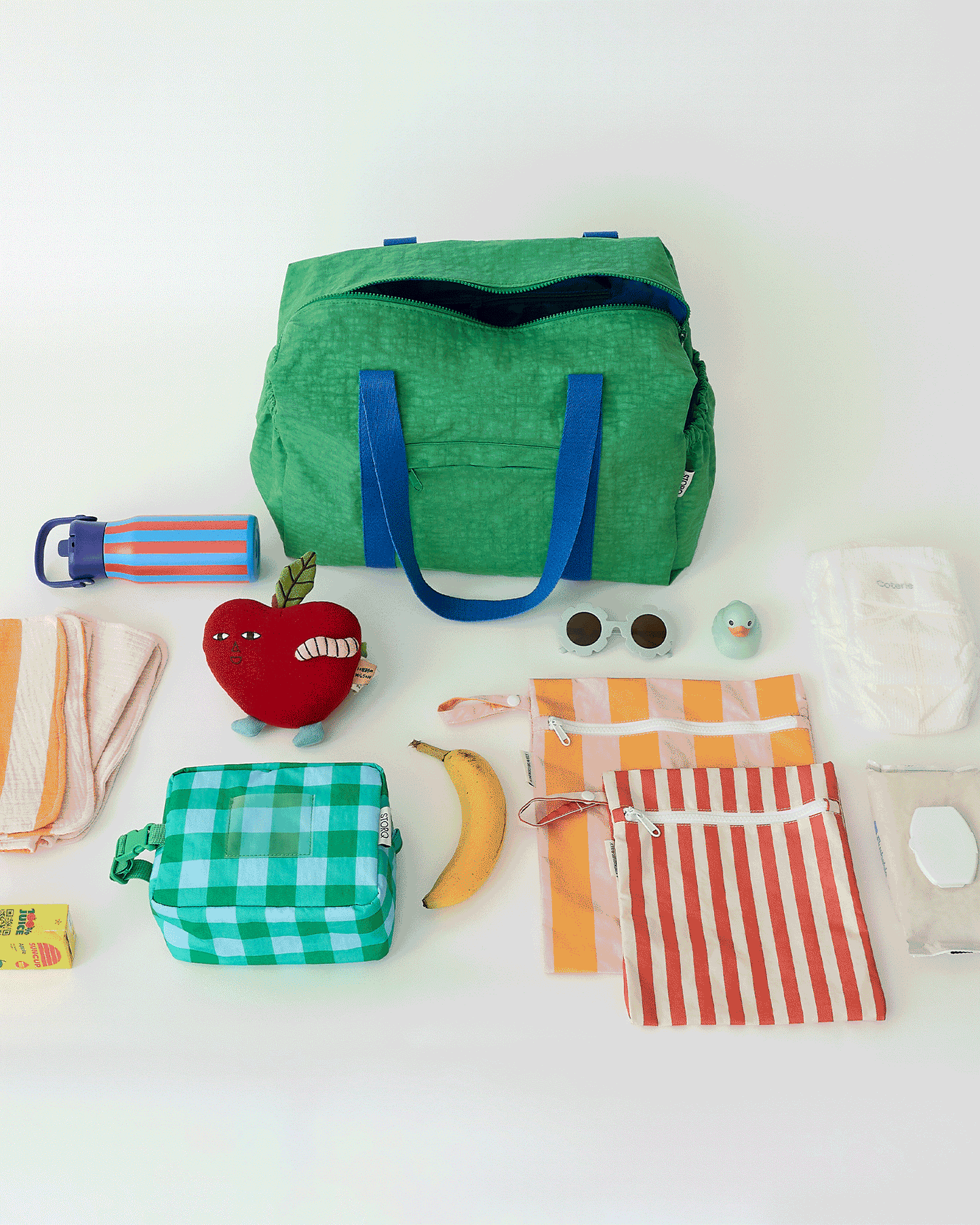 Animated GIF of Large Weekender Bag in Green packing up all the essentials, including Cool Kid Water bottle, Cool Kid Lunch box, Wet/Dry Bag Set, Pink Stripe Muslin Burp Cloths, Lovey, Diaper, Ducky toy, Shades, Water wipes and juice box, all on an off white background.
