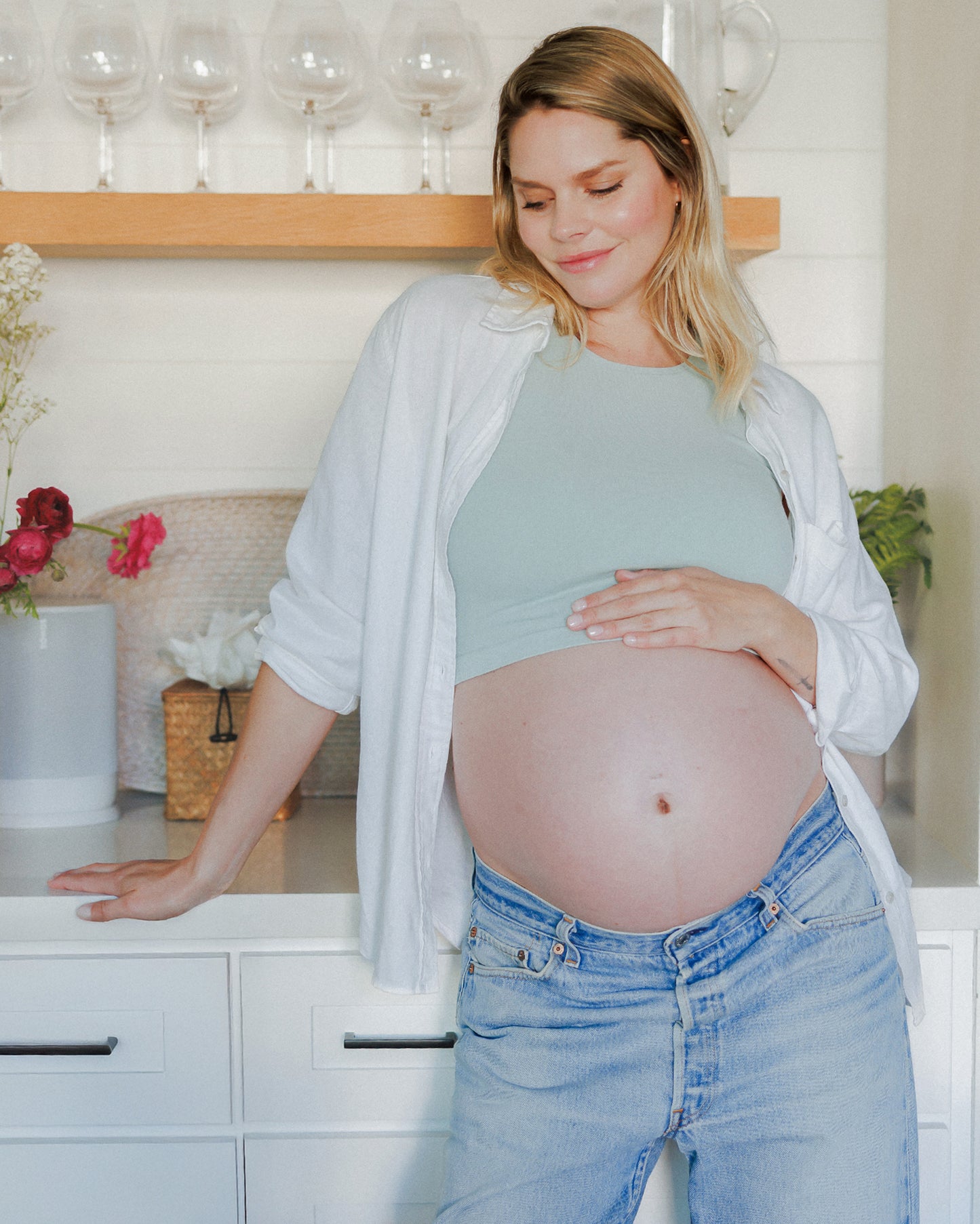 Model leaning on the counter while wearing the Sublime® Bamboo Maternity & Nursing Longline Bra Top in Aqua Mist @model_info:Anna is wearing a Small.