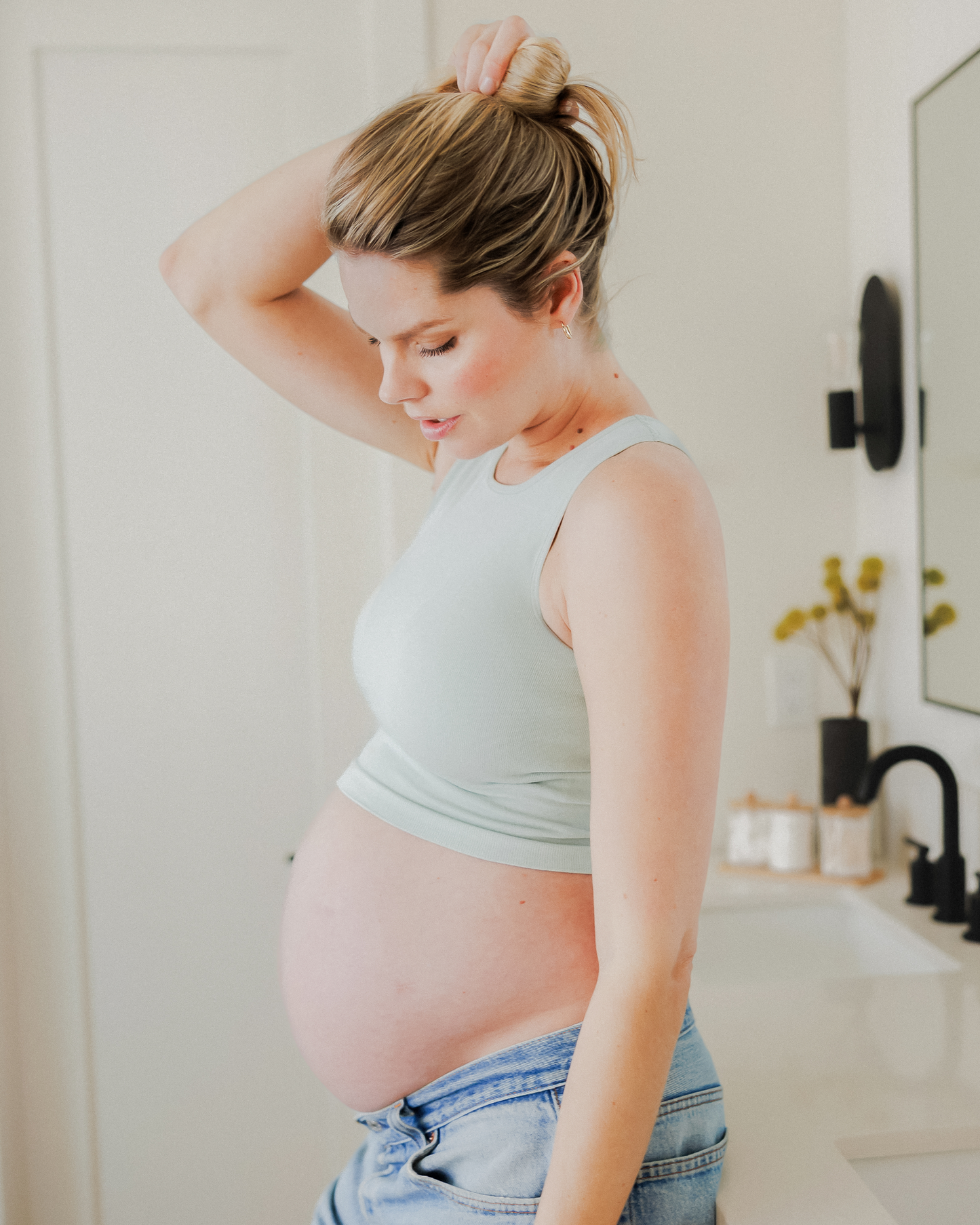 Model leaning on the bathroom counter while wearing the Sublime® Bamboo Maternity & Nursing Longline Bra Top in Aqua Mist