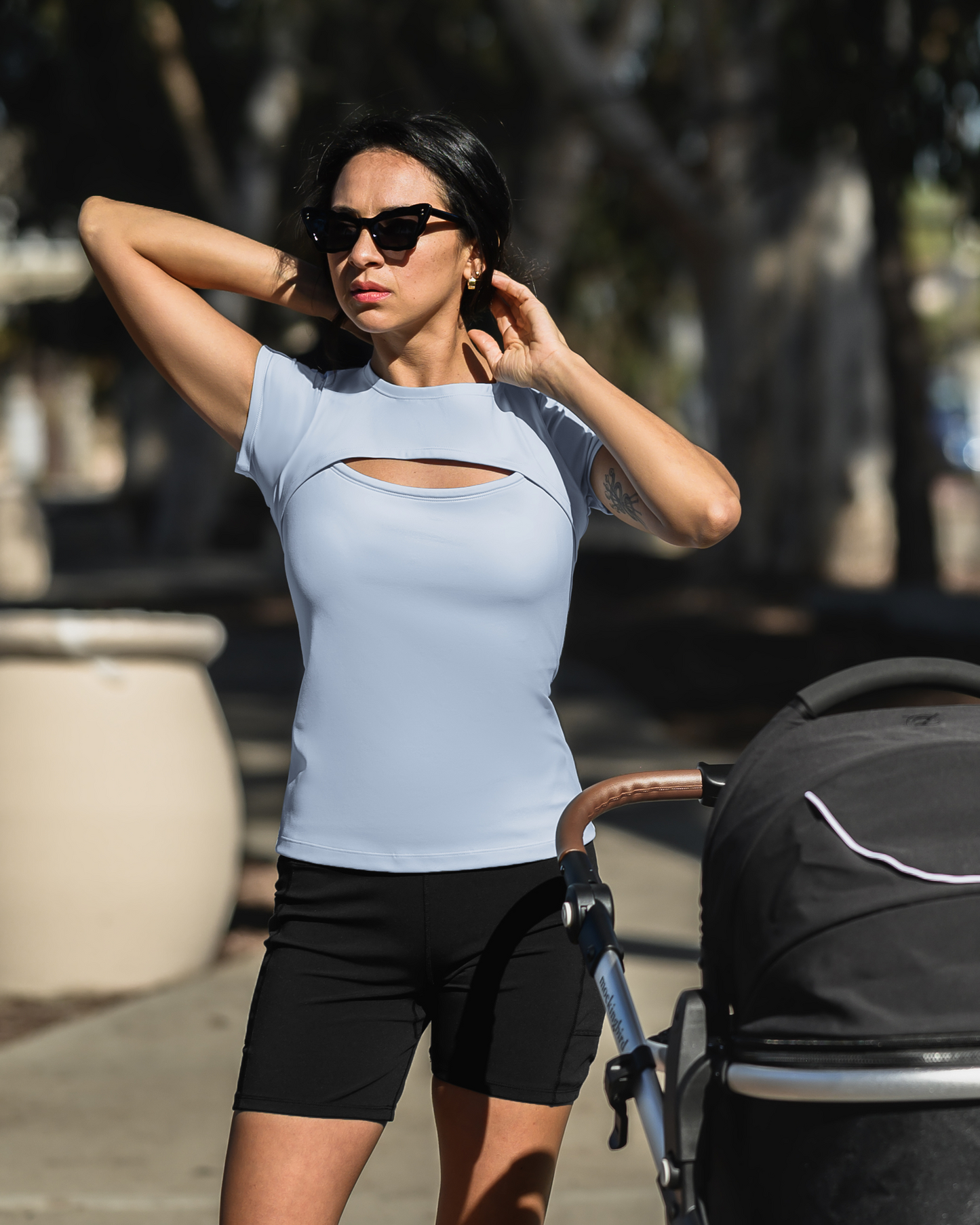 Model next to baby stroller wearing the Luna Active Cut Out Nursing Top in French Blue