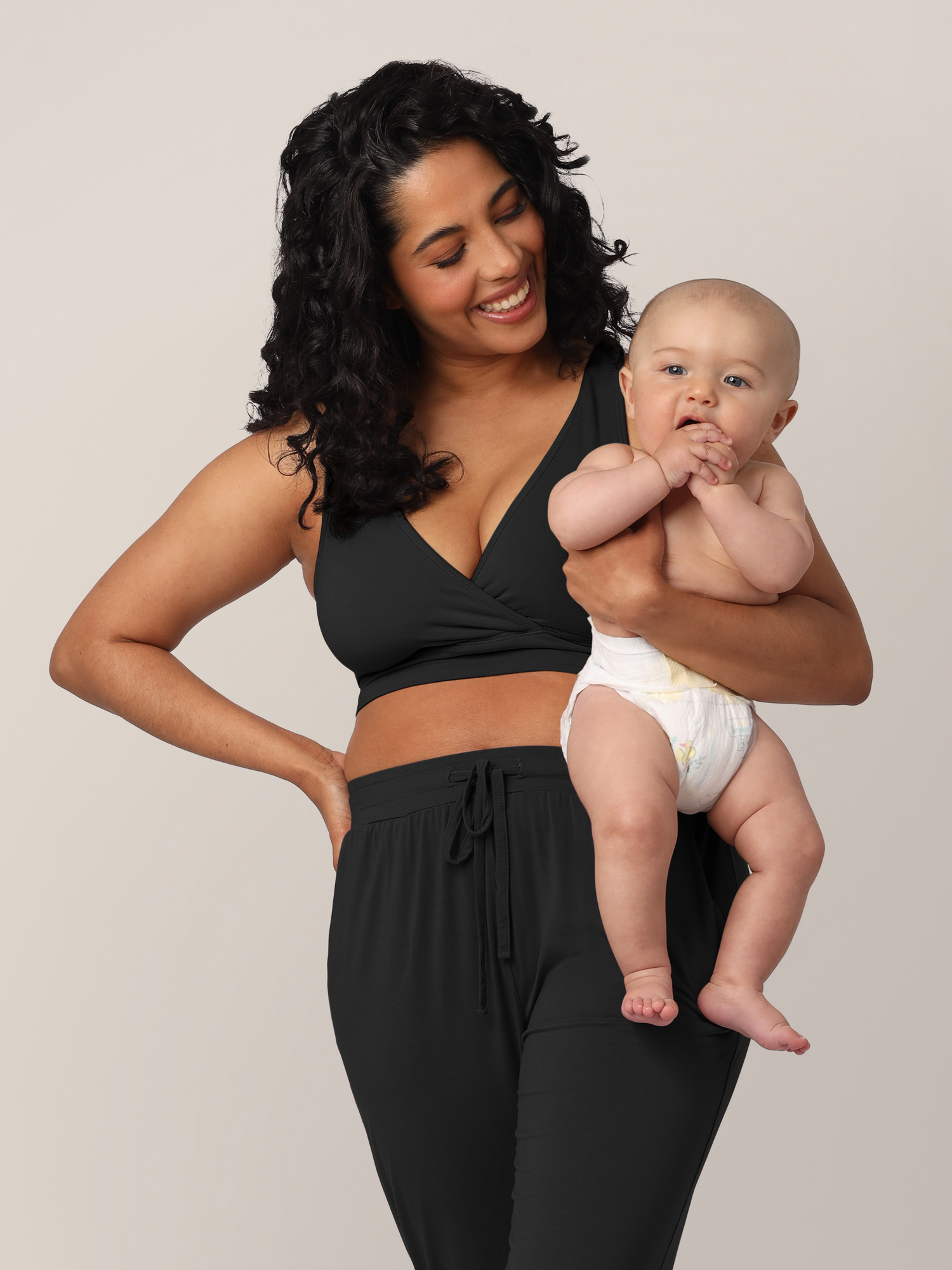 Model wearing the French Terry Nursing Bra in Black and holding her infant @model_info:Zakeeya is wearing a Small.