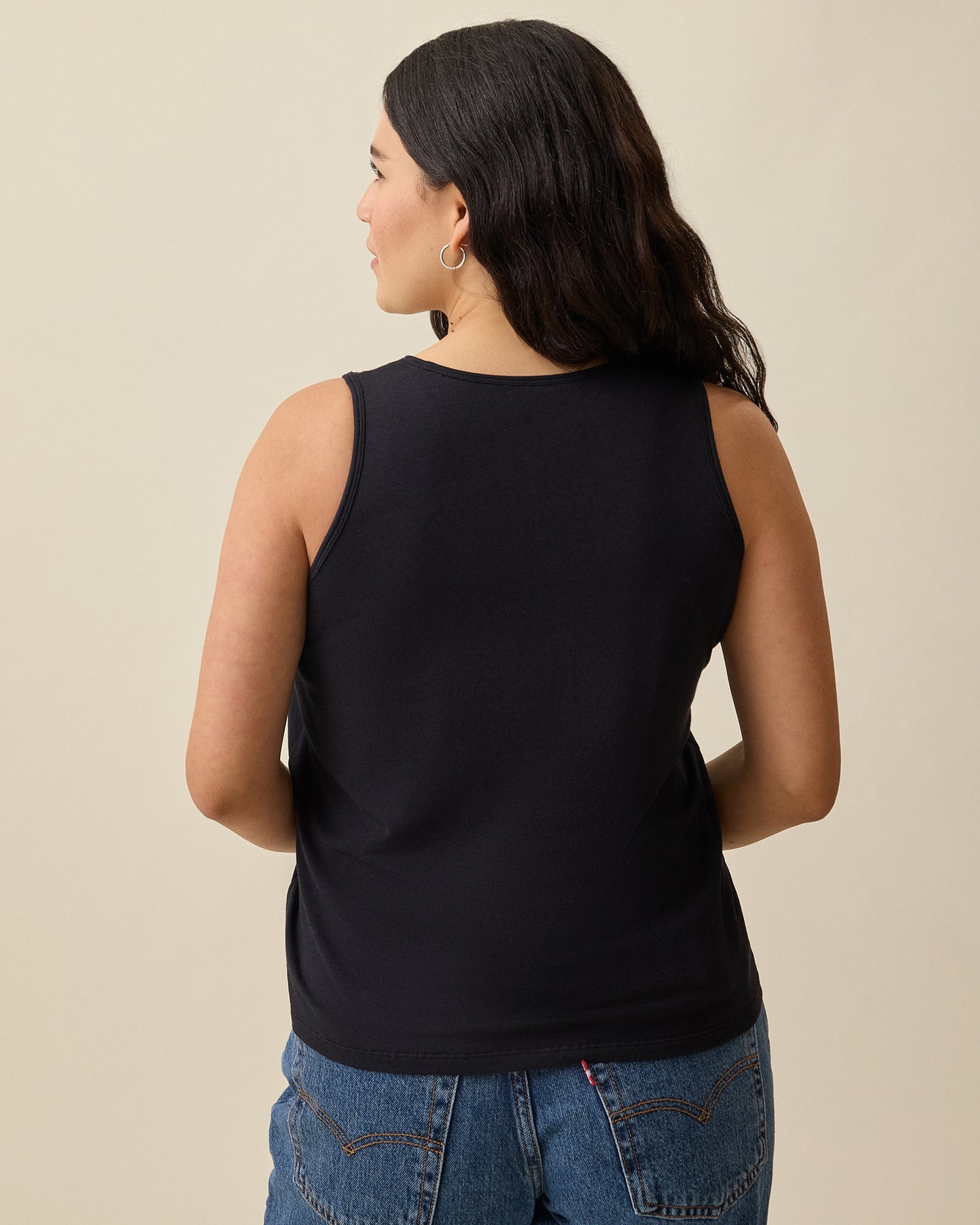 Model is showing back view of Modal Signature Nursing Tank in Black on a beige background.