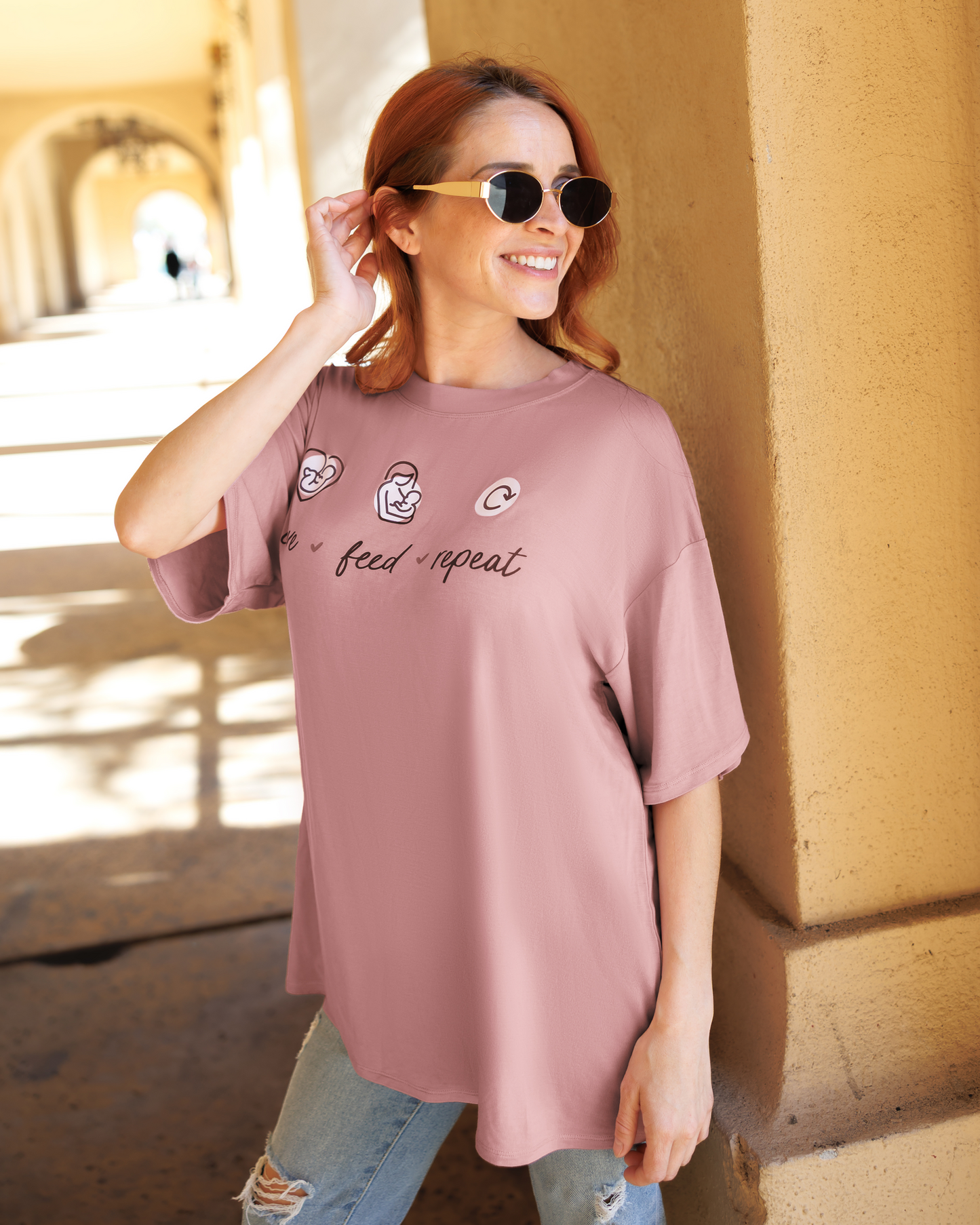 Model outside wearing Oversized Graphic Tee in Love Feed Repeat, paired with Jeans