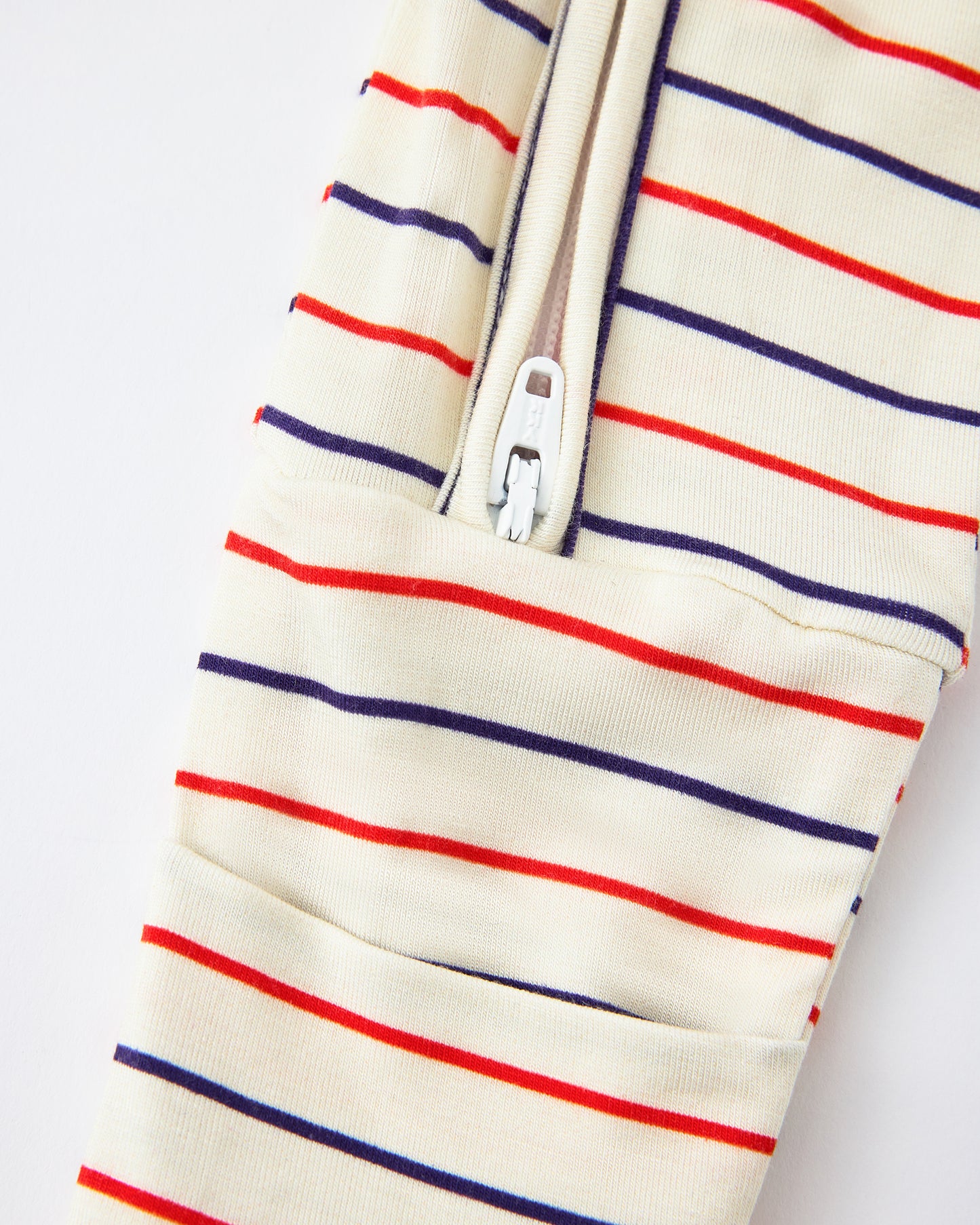 Close up of zipper detail on Bamboo Baby Pajama in Pencil Stripe on a beige background