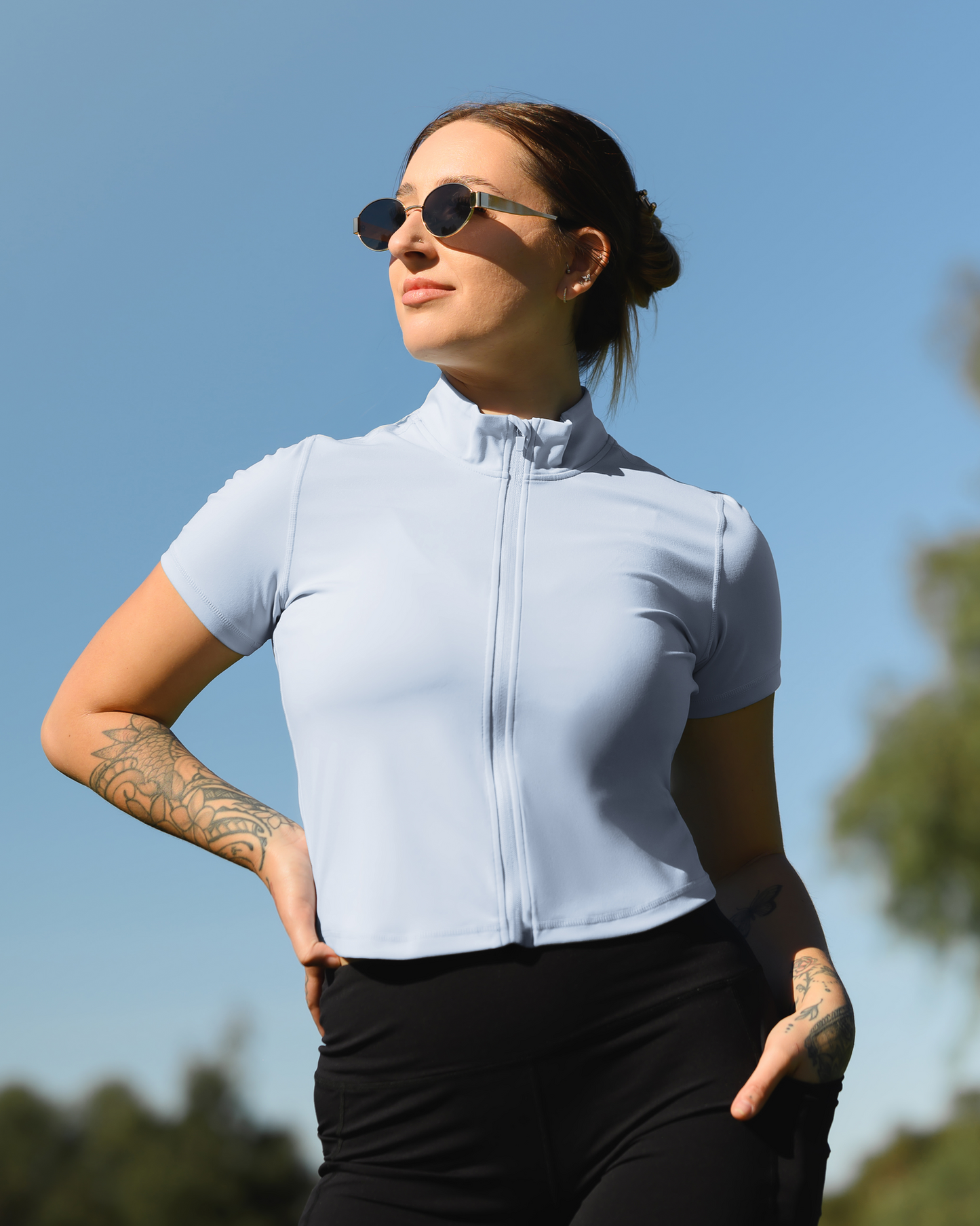Model standing outside wearing the Presley Active Zip Front Nursing Top in Light Blue @model_info:Anna is wearing a Medium.