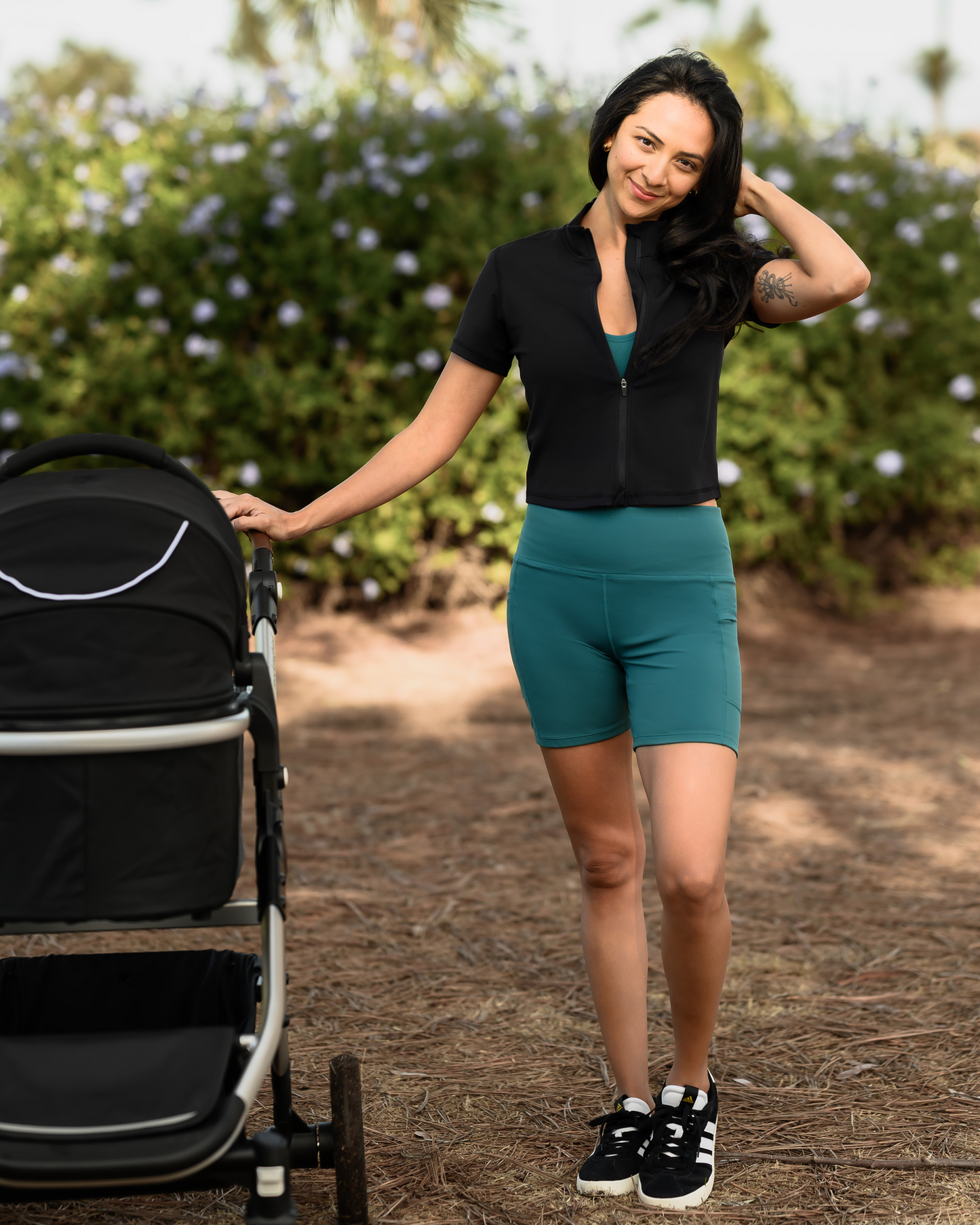 Model pushing baby stroller while wearing the Stevie Active Postpartum Bike Short in Teal with the Presley Active Zip Front Nursing Top
