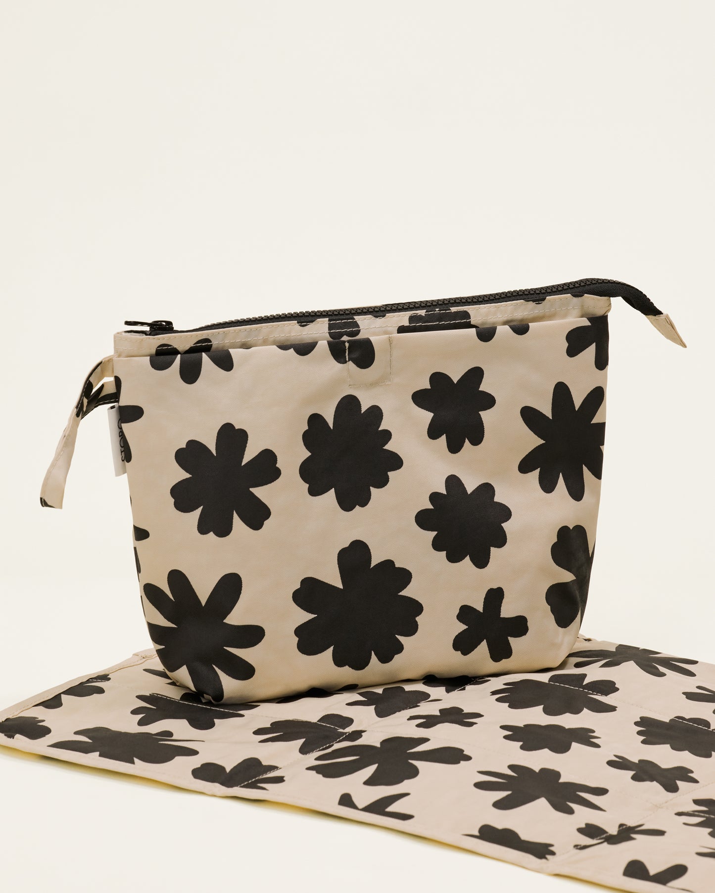 Quick Change Kit Bag in Cream Chamomiles print, on a neutral background, with the included changing pad open under it