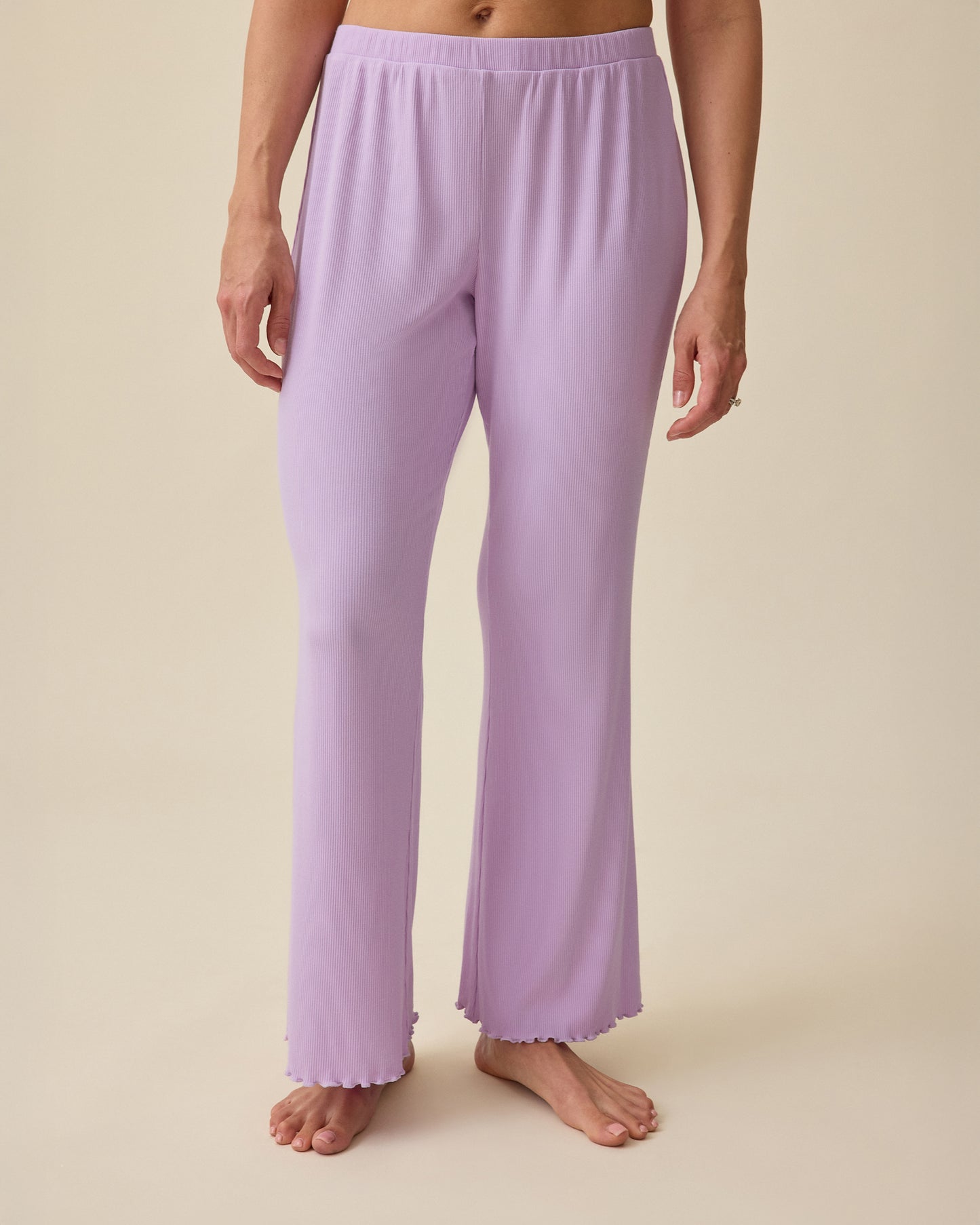 Model wearing Ribbed Modal Lounge Pant in Lavender on a beige background.