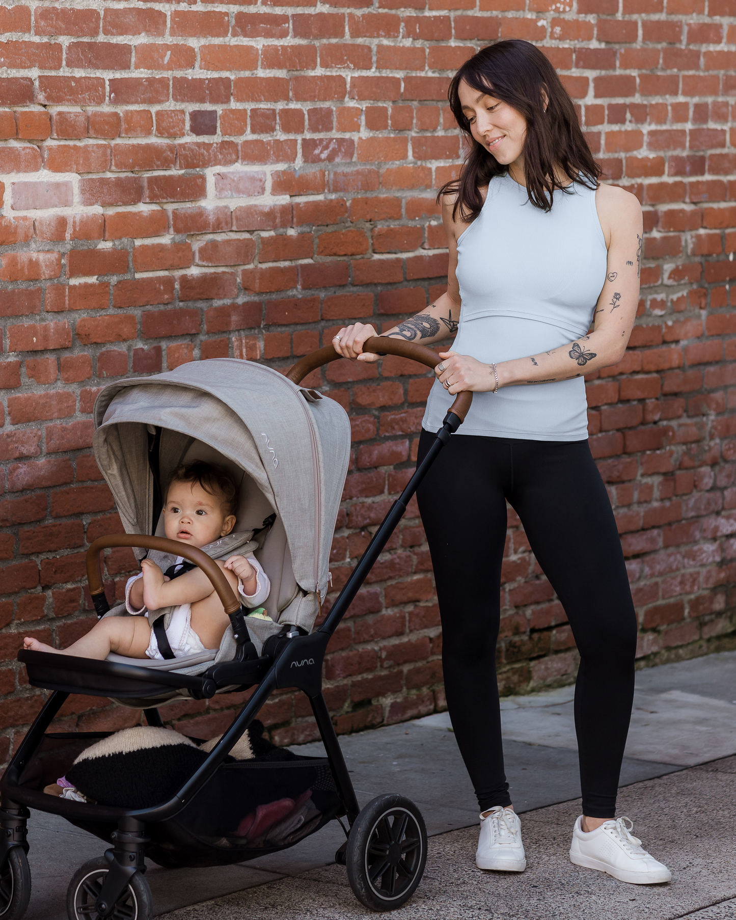 Model outside wearing the Ribbed Bamboo Racerback Nursing Tank in French Blue paired with the Louisa Legging, pushing baby in stroller