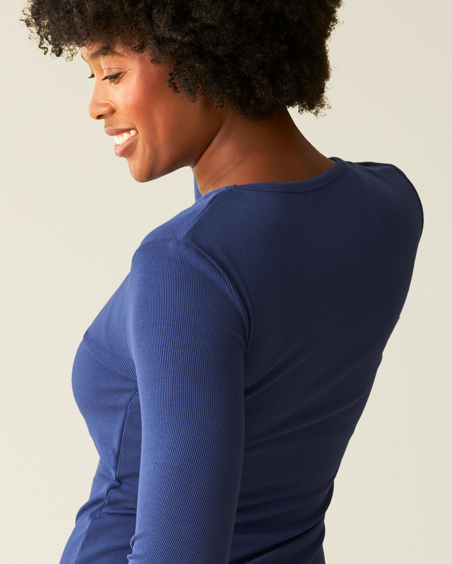 Side back view of woman wearing the Ribbed Bamboo Long Sleeve Nursing T-shirt in Deep Blue on beige background