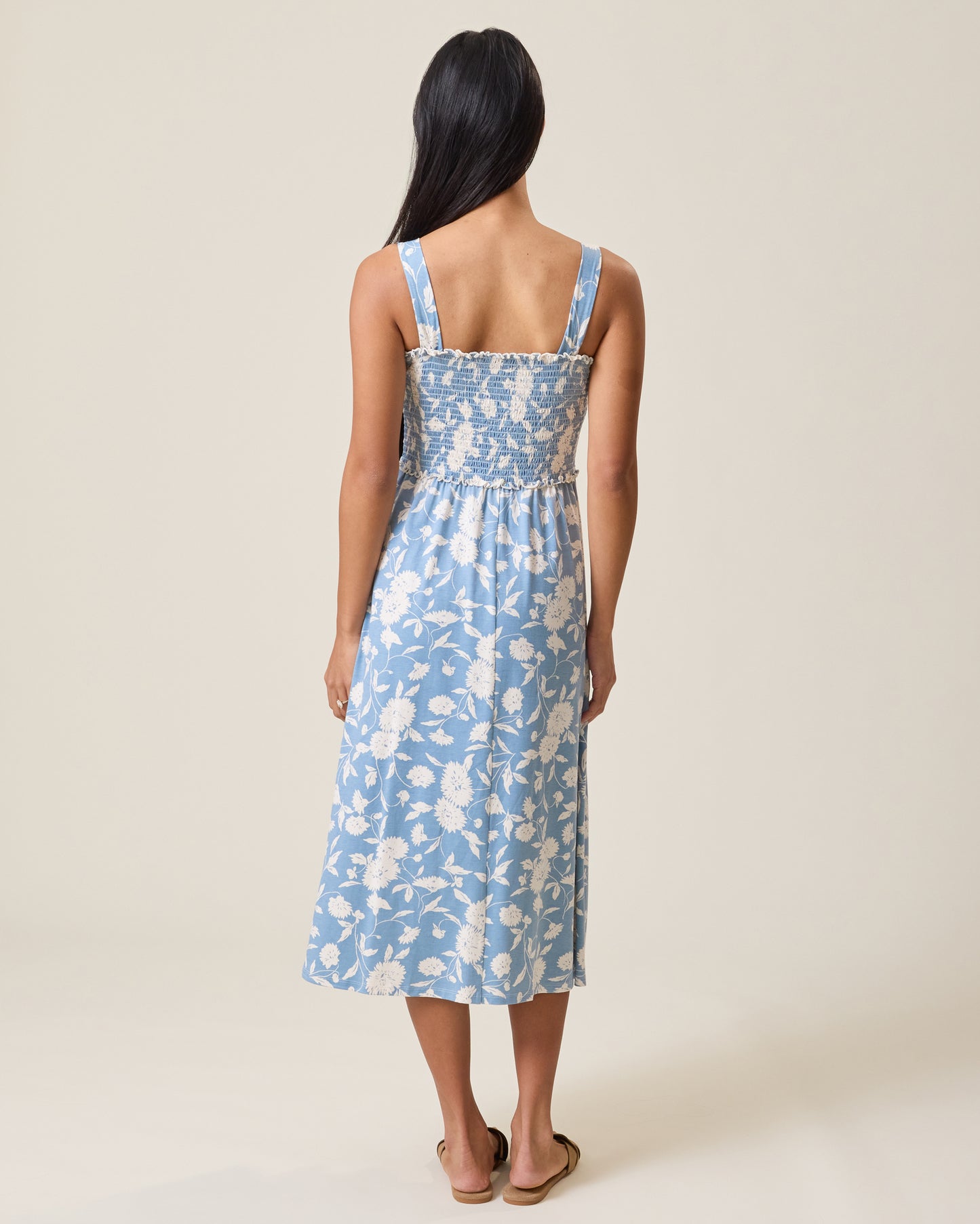 Woman wearing a blue floral dress on a plain background