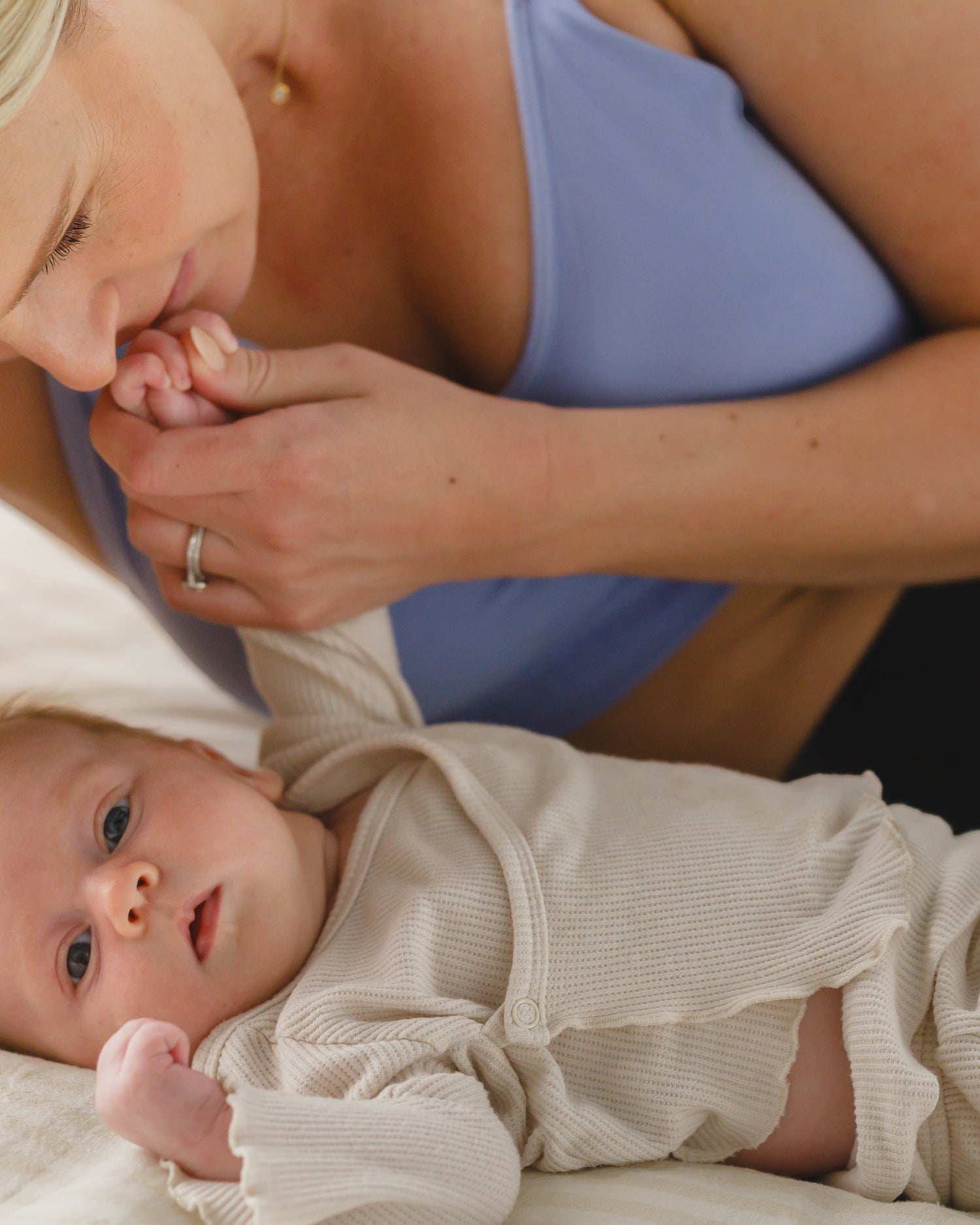 Model wearing the Simply Sublime® Nursing Bra in Blue Wisteria, laying on bed with baby